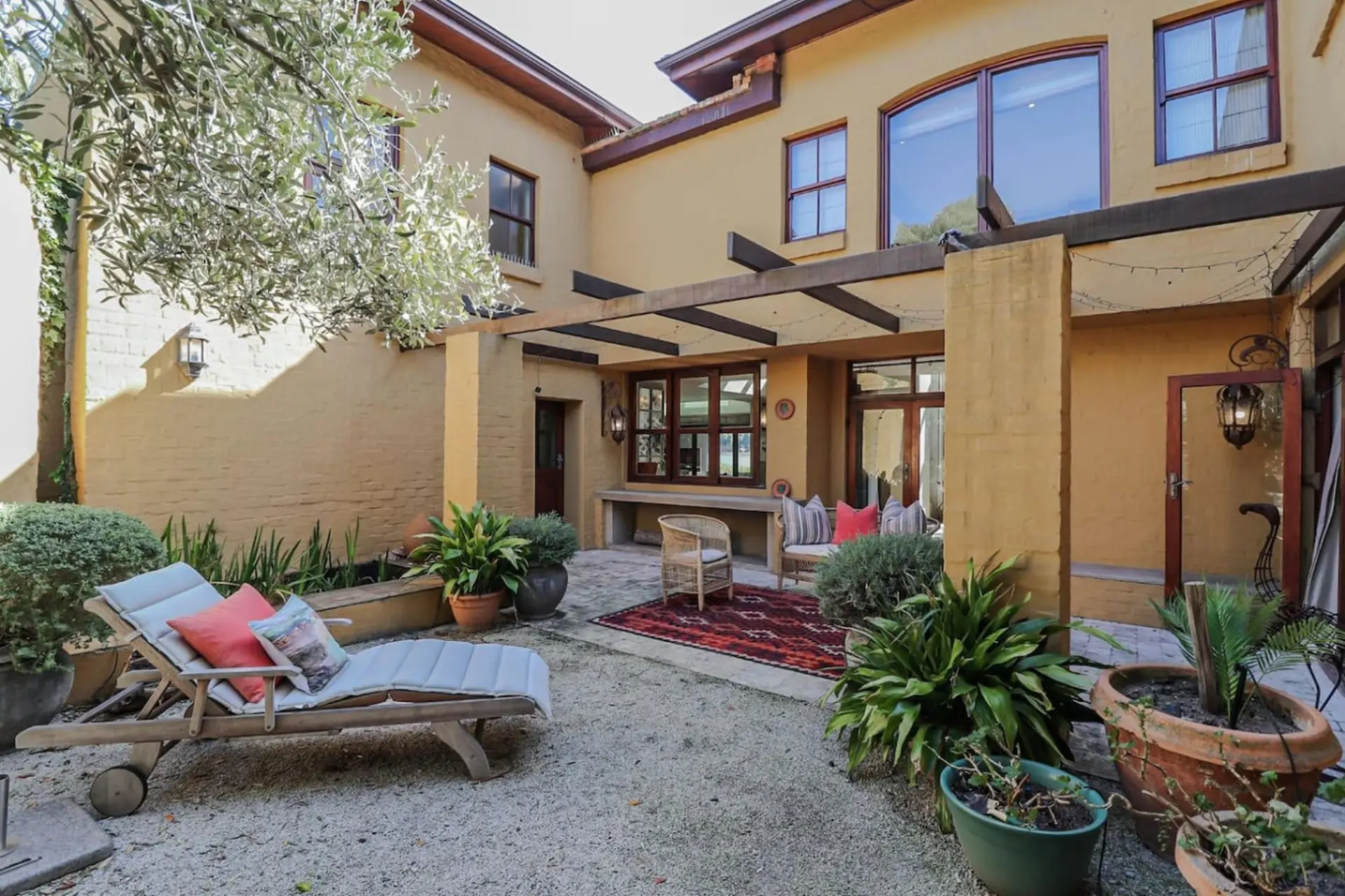 Outdoor courtyard with patio furniture, plants, and a stucco house.