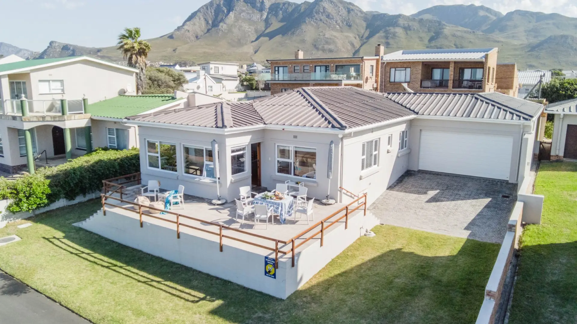 A light grey single-story home with a large deck and dining table.