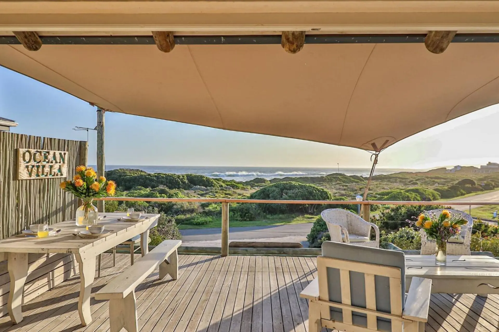 Deck with dining set and ocean view, featuring a "OCEAN VILLA" sign.