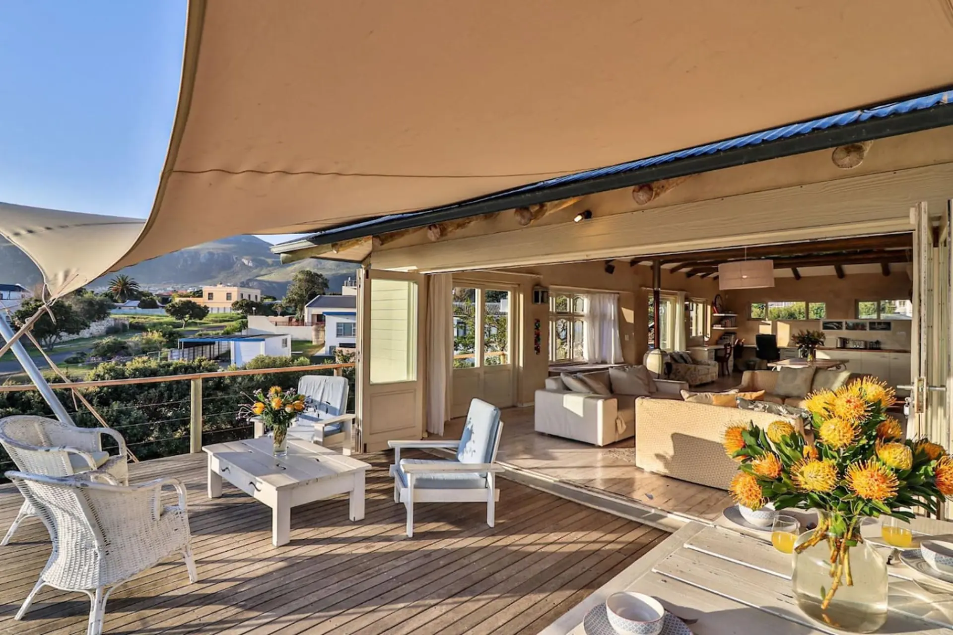 A bright and airy home with a large outdoor deck, overlooking a coastal town and mountains.