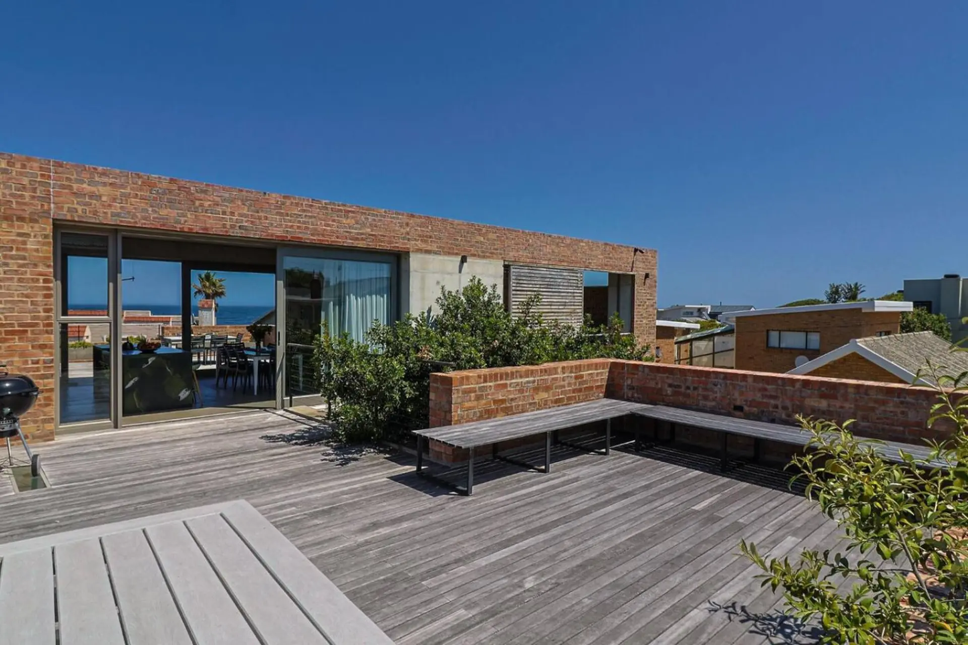 A modern brick house with a wooden deck and ocean view.