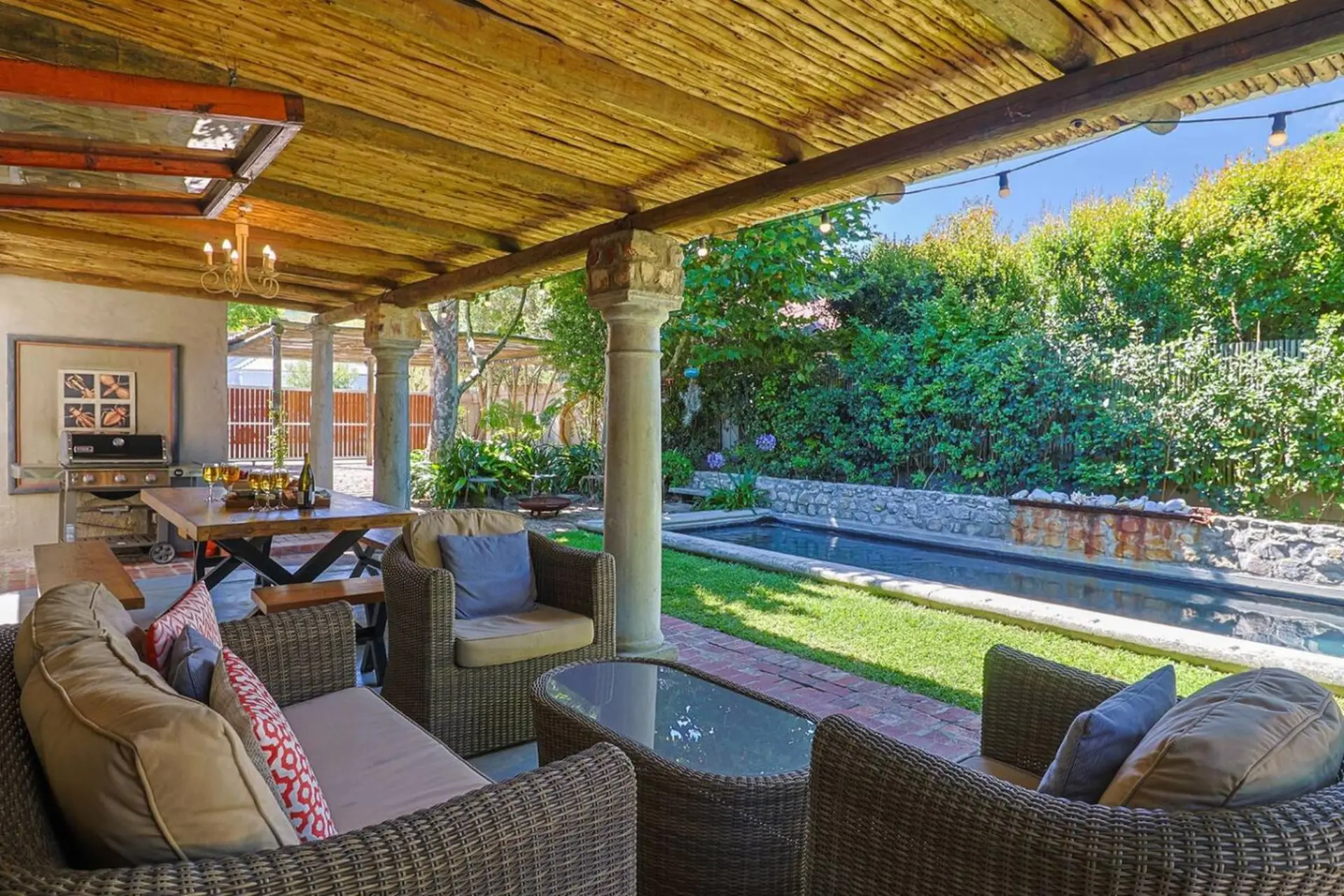 Outdoor patio with lounge seating, dining table, and a long, narrow pool.
