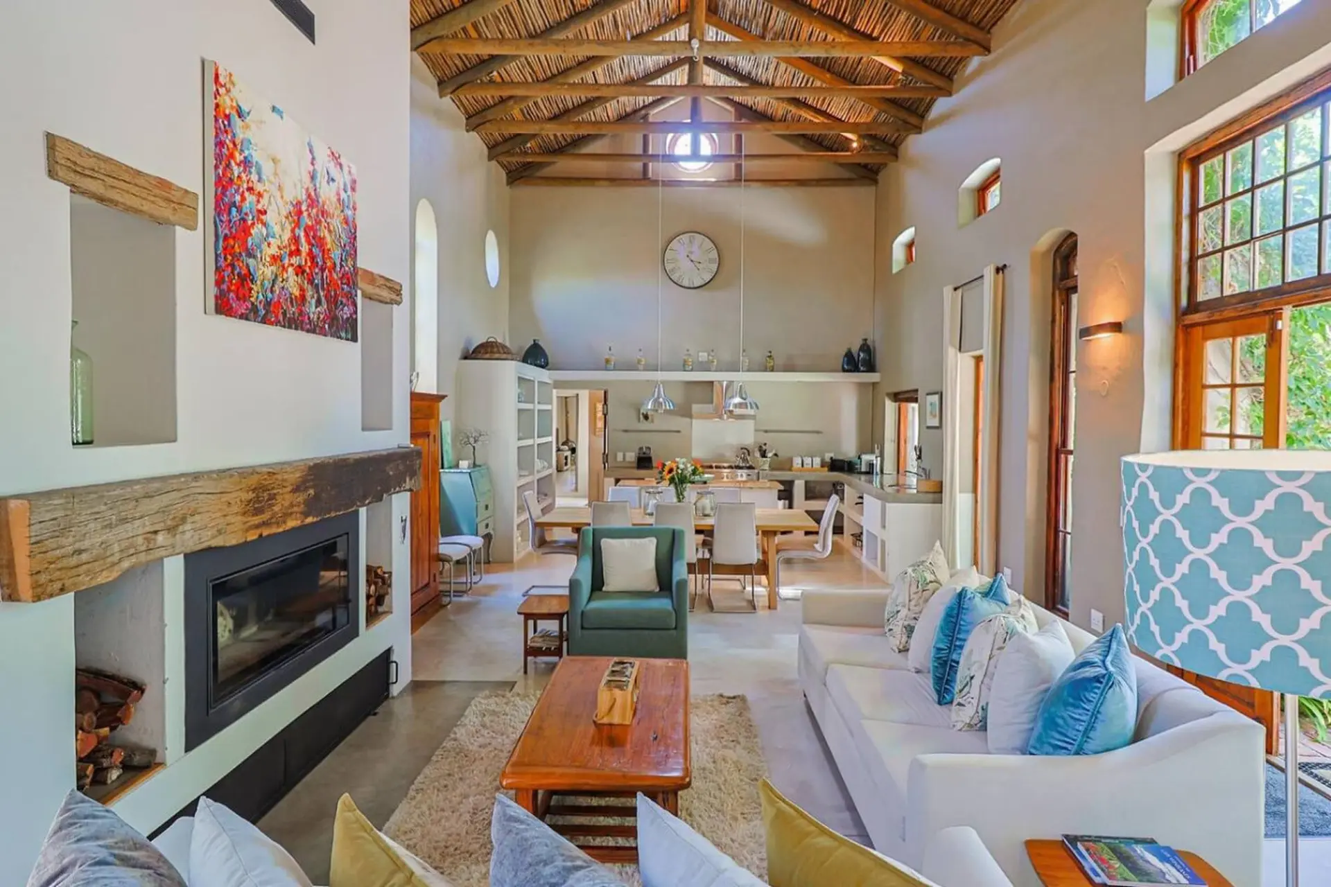 Spacious living room with high ceiling, fireplace, dining area, kitchen, and seating.