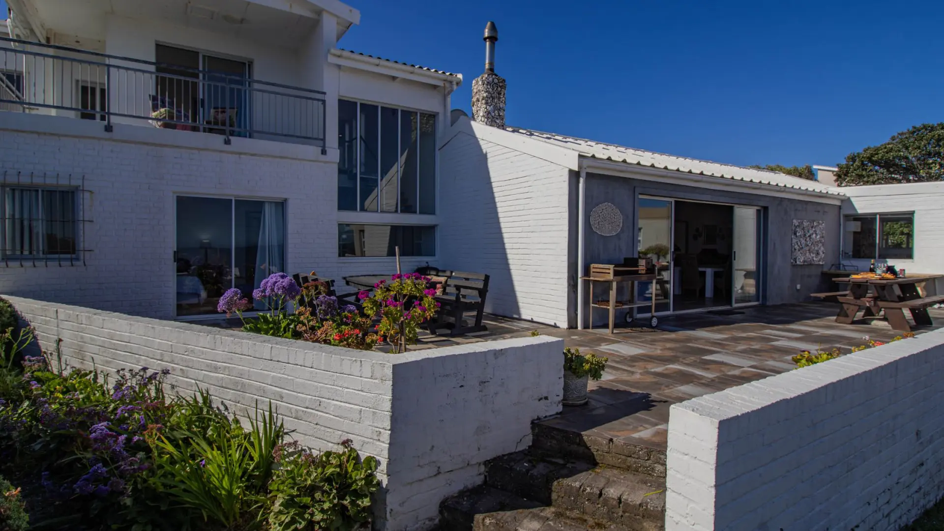 White brick house with patio and picnic table.