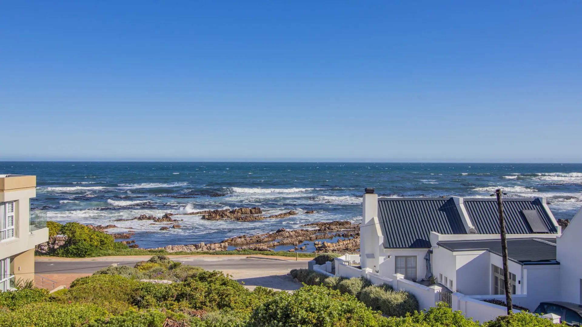 Ocean view from a modern white house with a dark roof.
