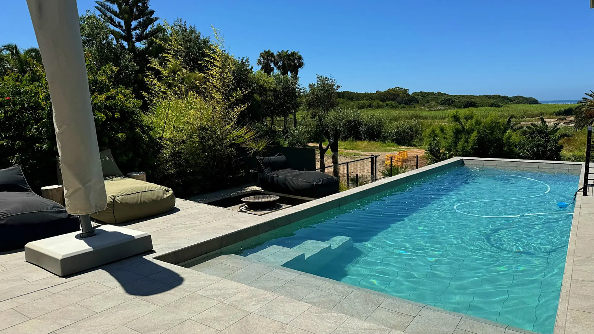 An outdoor pool with lounge chairs and a fire pit.