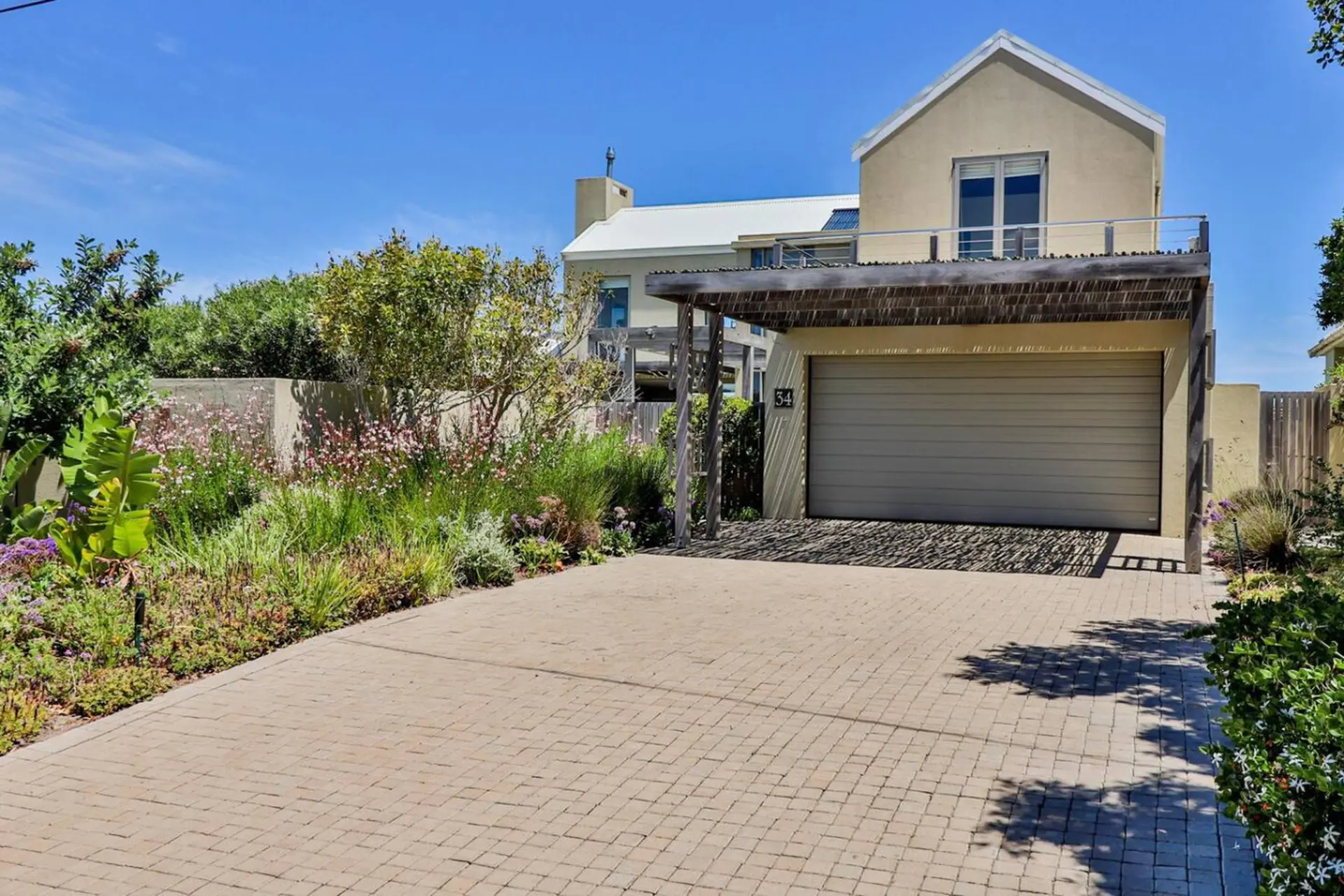 A modern home with a light yellow facade and a wide garage door.
