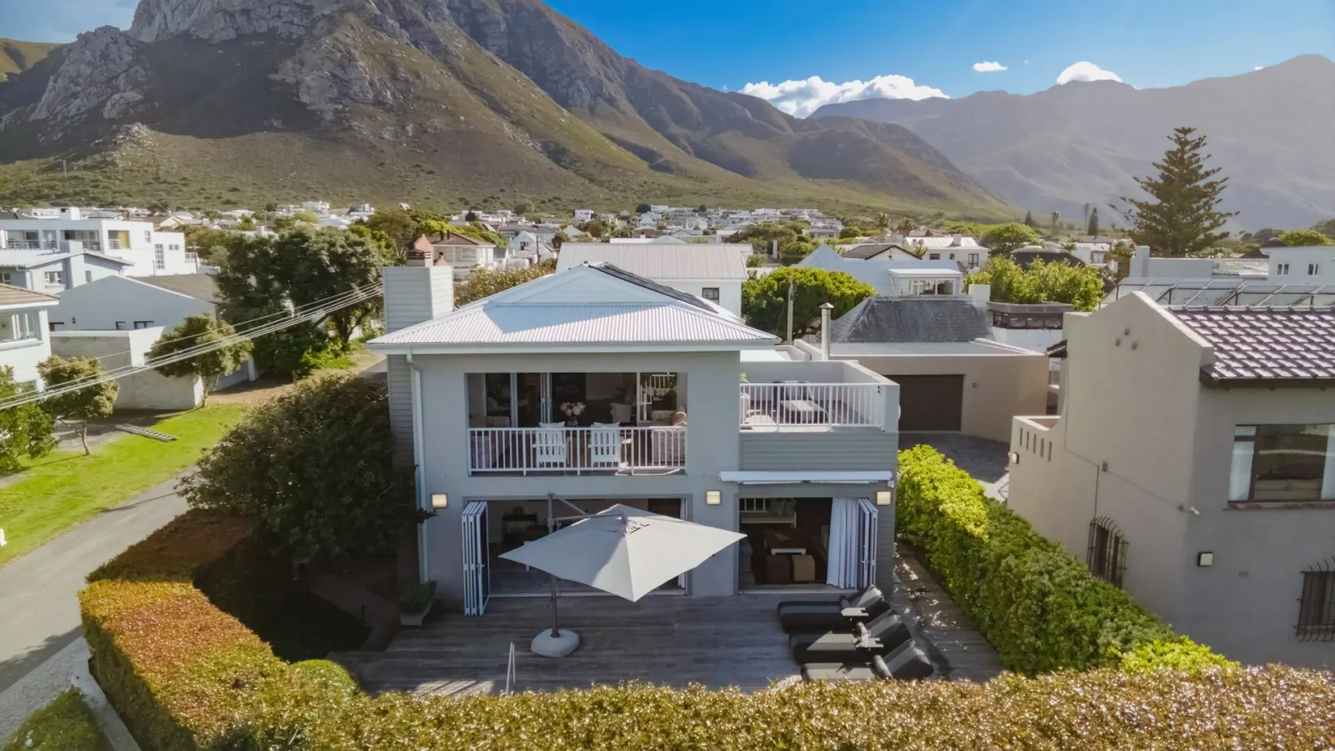 Modern home with a balcony and patio, overlooking mountains.