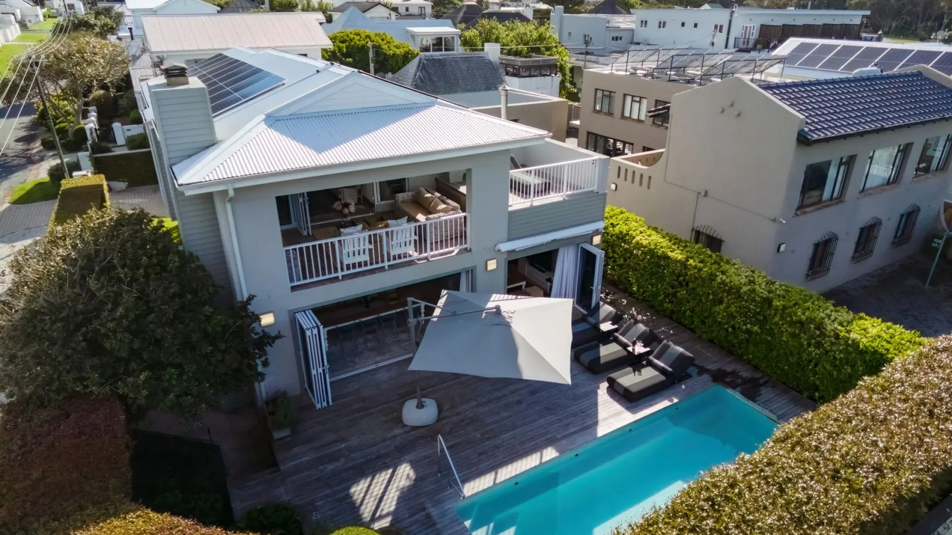 Aerial view of a modern house with a pool and lounge chairs.