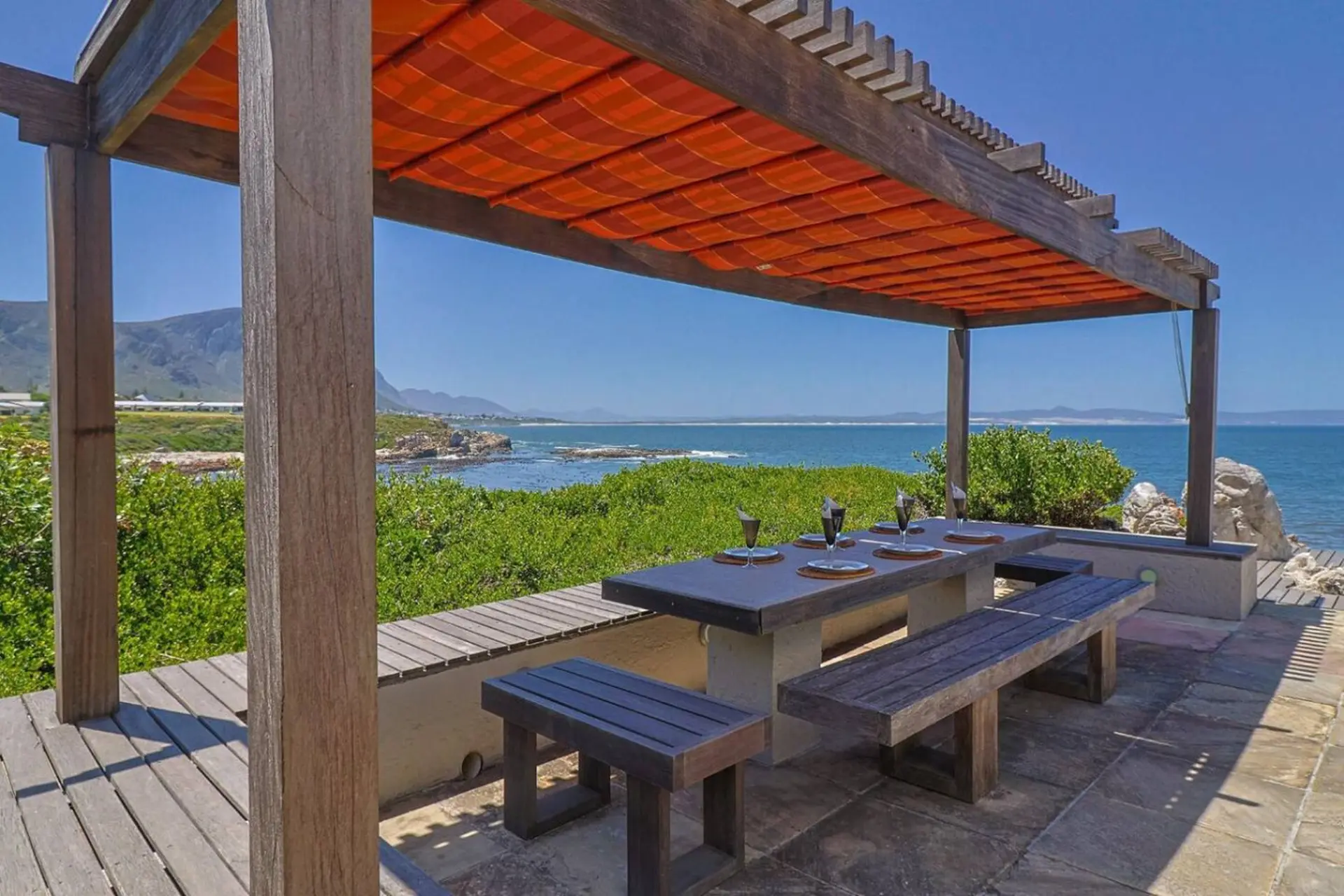 Pergola with dining table overlooking the ocean and mountains.