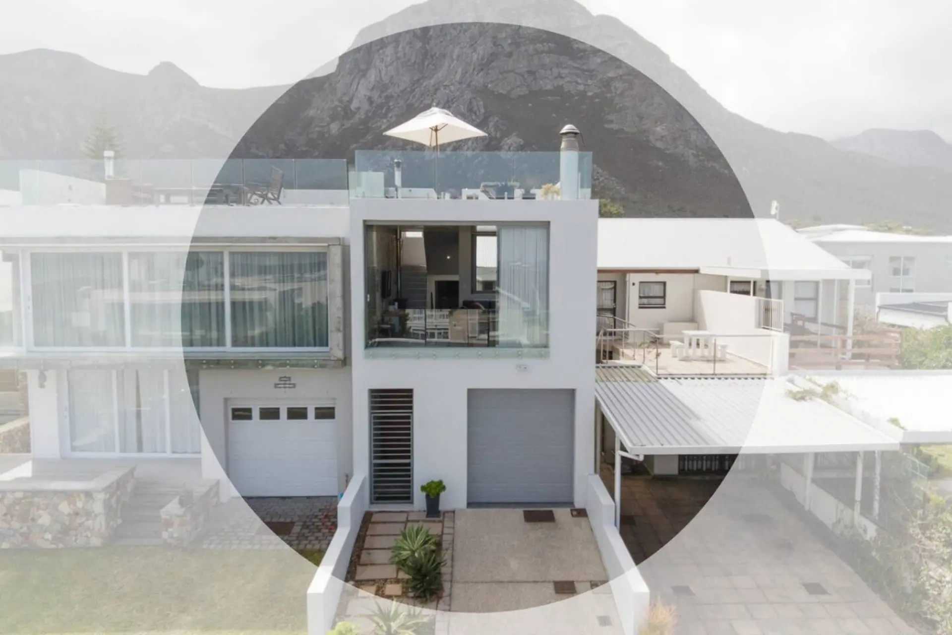 Modern house with a rooftop terrace and mountain views, featuring a garage and outdoor seating area.