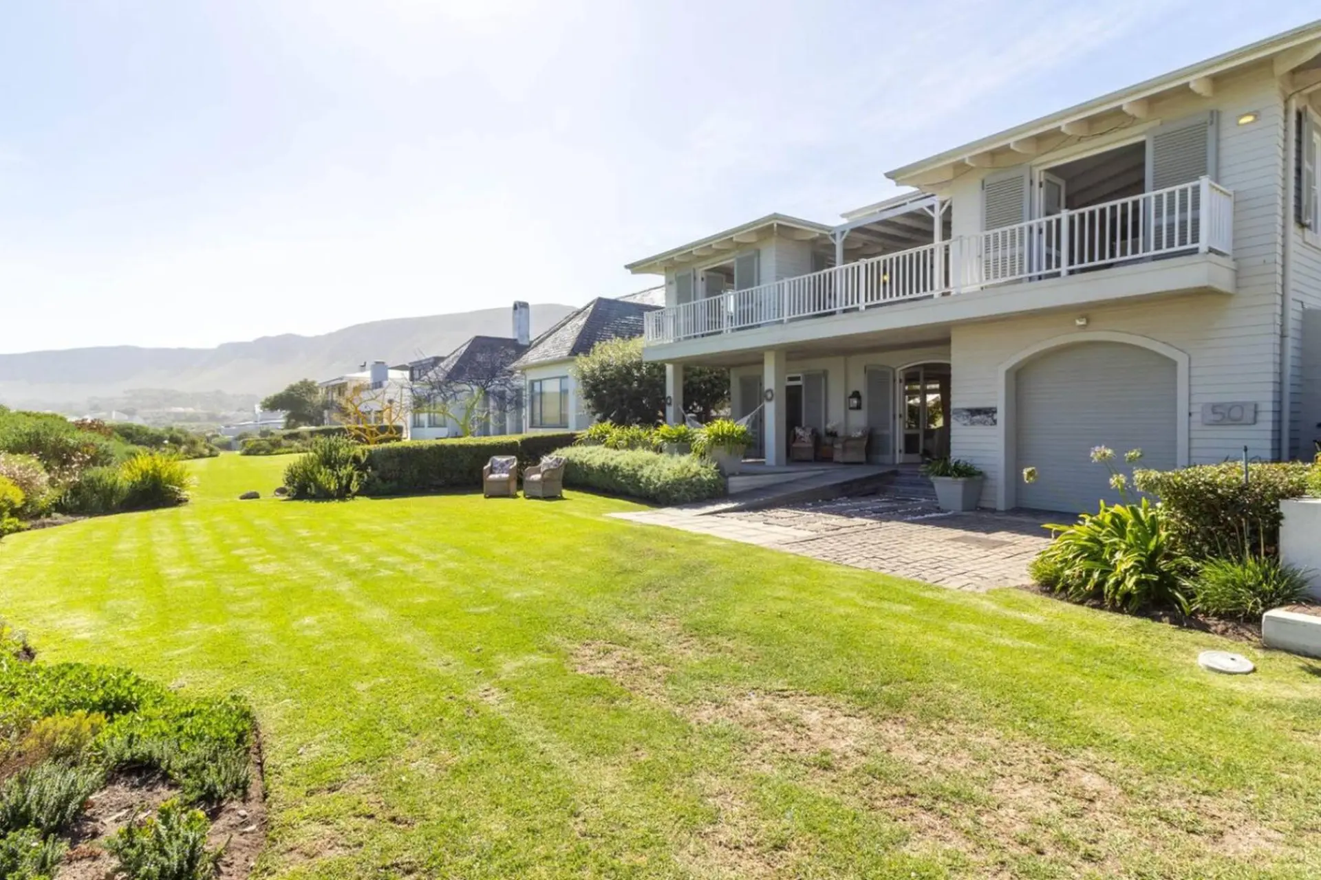 A house with a large lawn and mountains in the background.