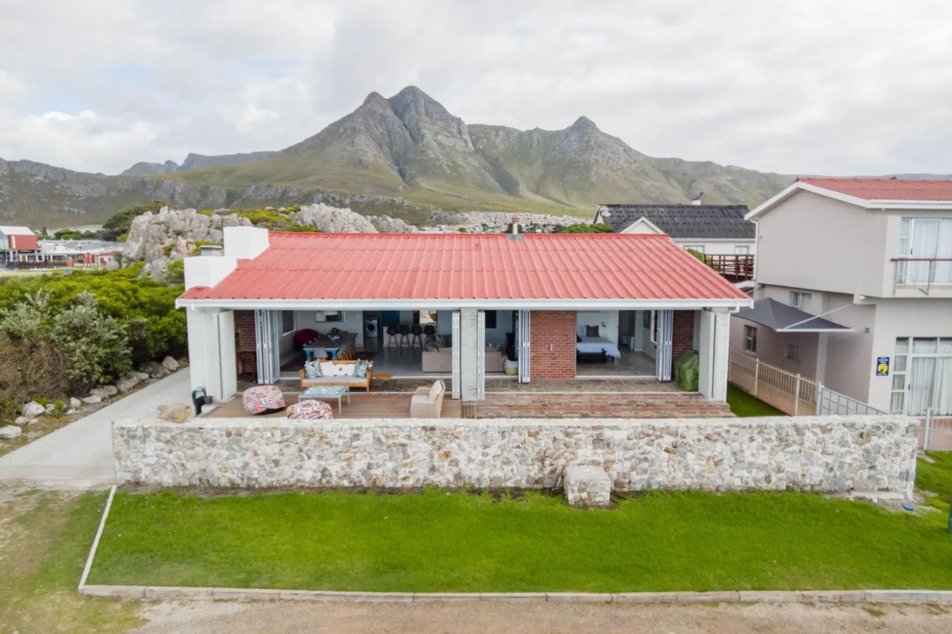 A beachfront home with a red roof, featuring open-plan living and large windows.