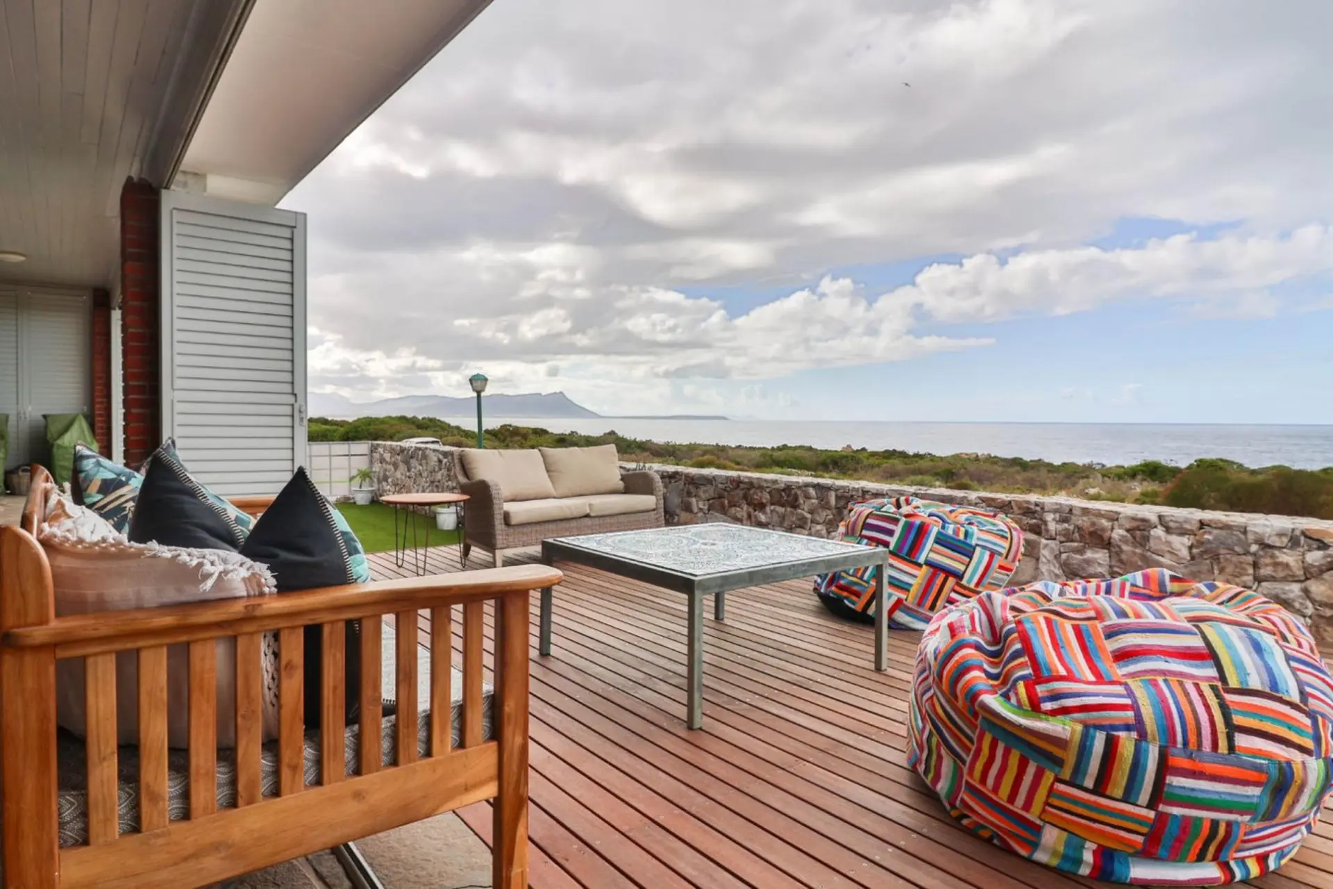 A modern deck with colorful bean bags overlooks the ocean on a cloudy day.
