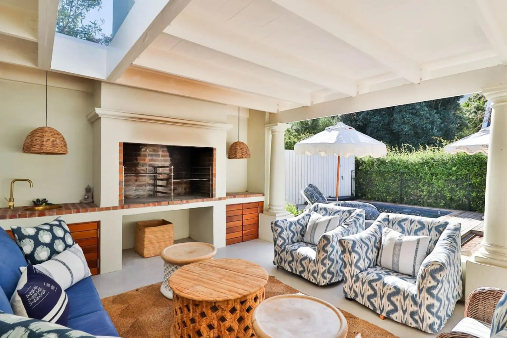 Outdoor patio with a fireplace, seating, pool, and umbrellas.