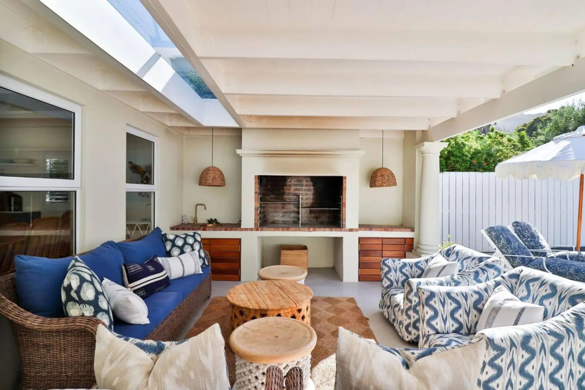 Outdoor patio with a blue sofa, patterned armchairs, and a fireplace.