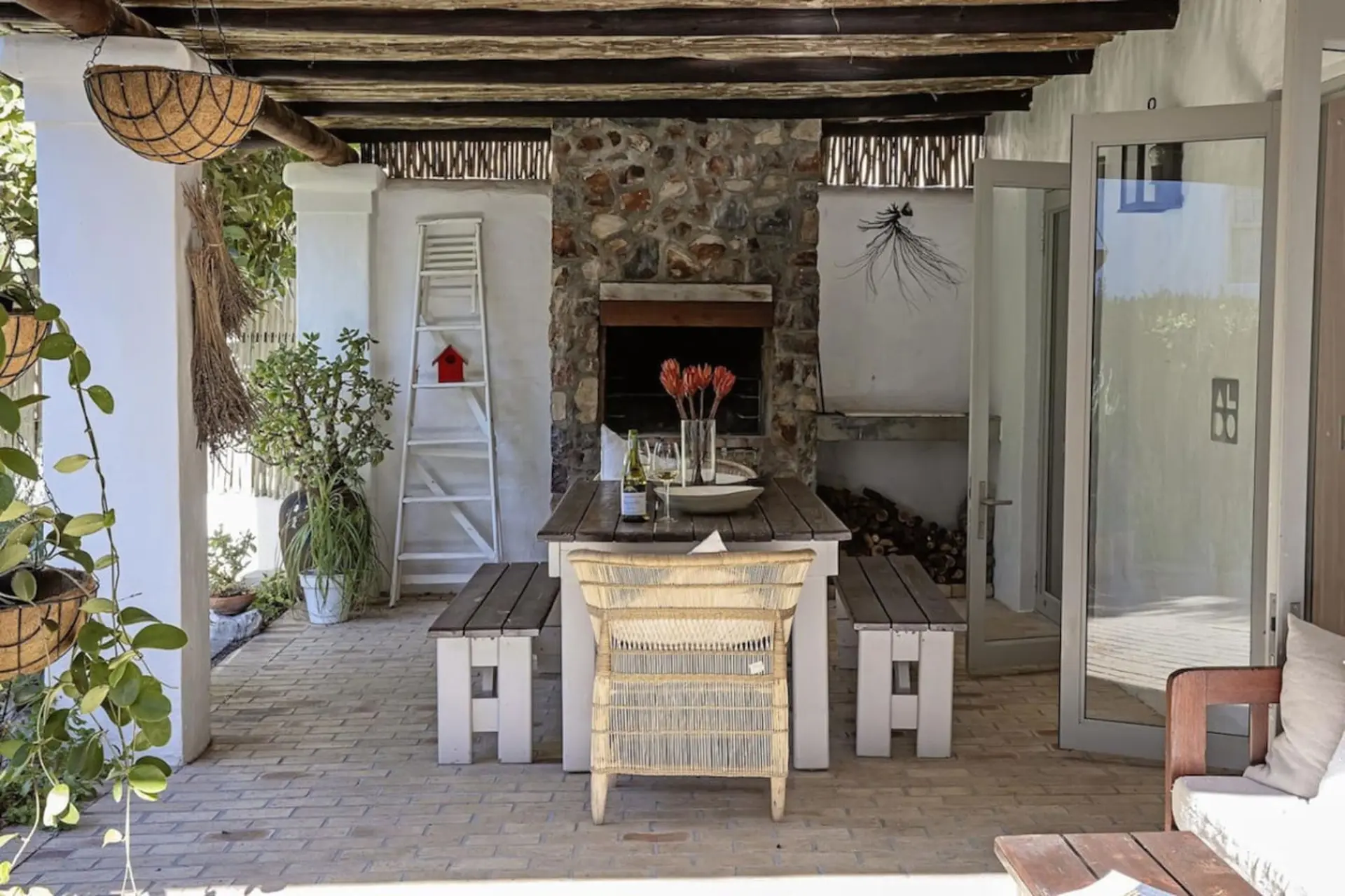 Outdoor patio with fireplace, dining table, benches, and chairs.