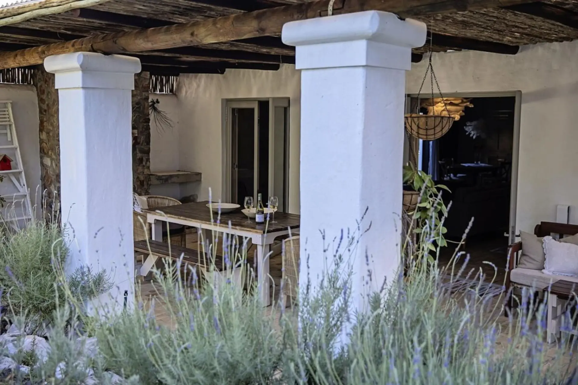 Outdoor patio with a dining table, bench, and chairs, surrounded by lavender plants.