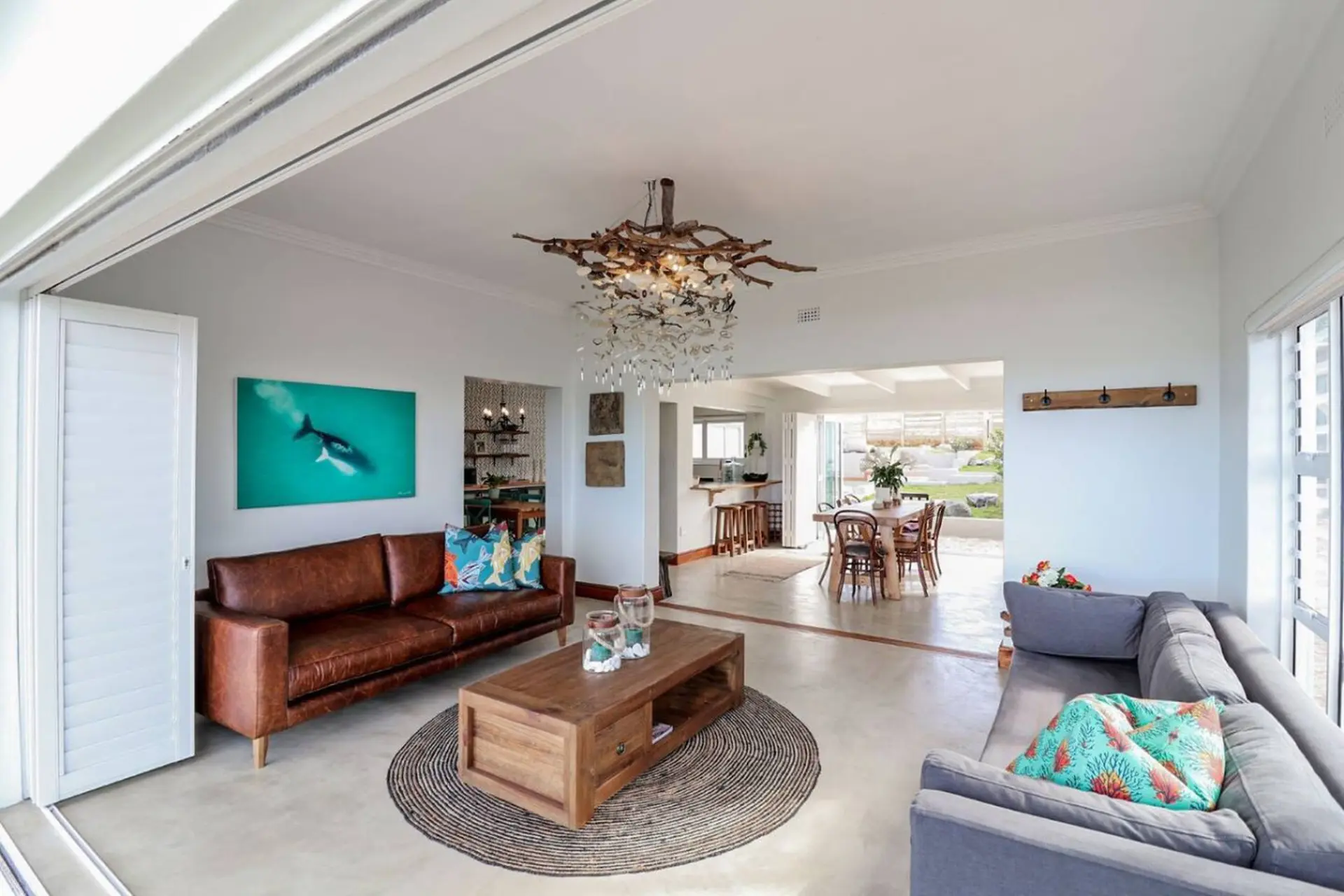 Living room with leather sofa, coffee table, and dining area with ocean view.