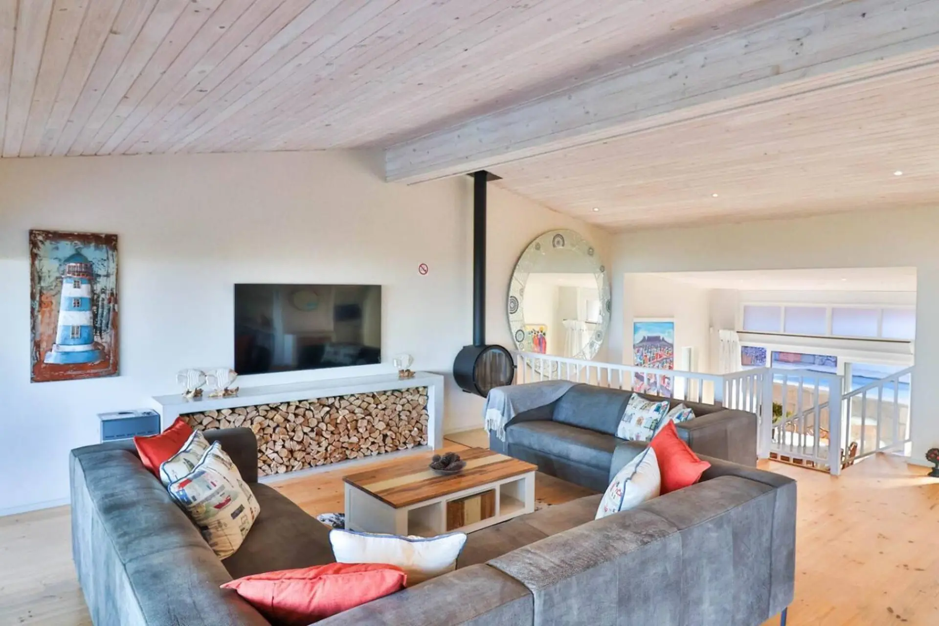 A spacious living room with a sectional sofa, fireplace, and view of the beach.