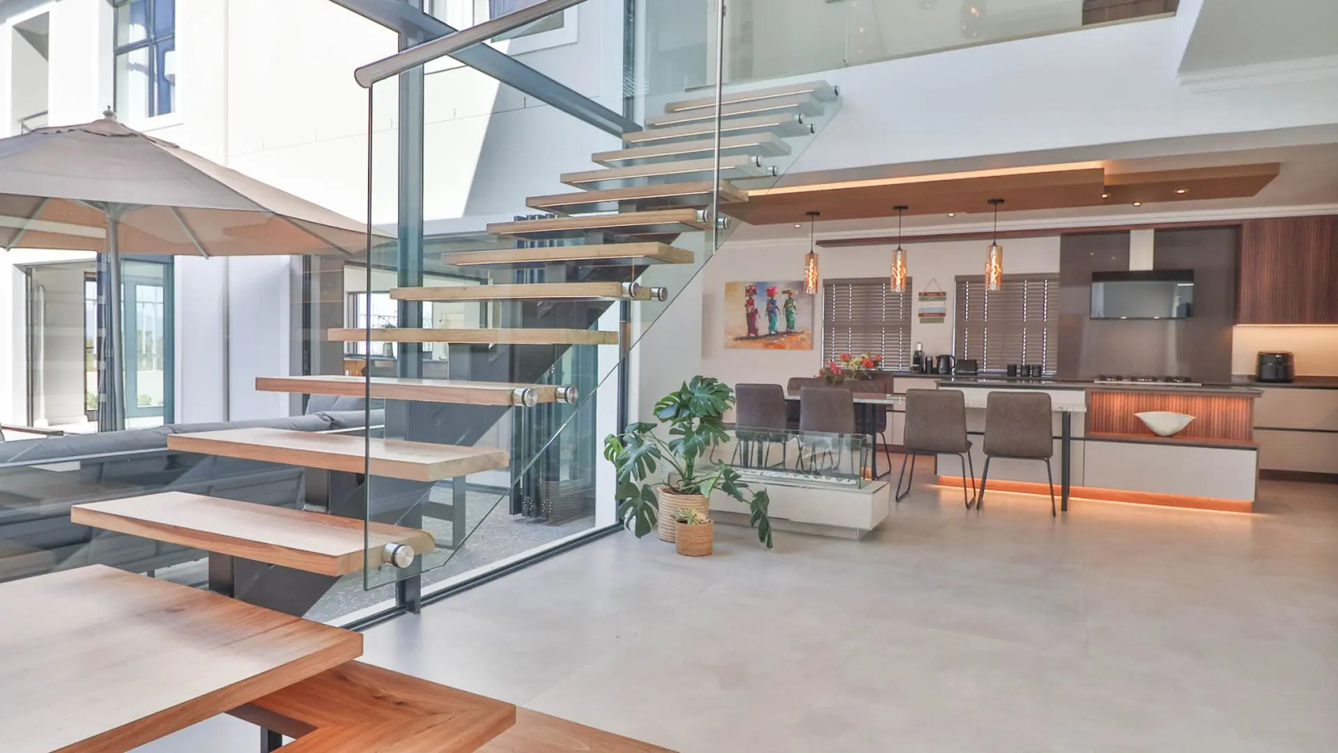 Modern living room with floating wooden stairs and a sleek kitchen.