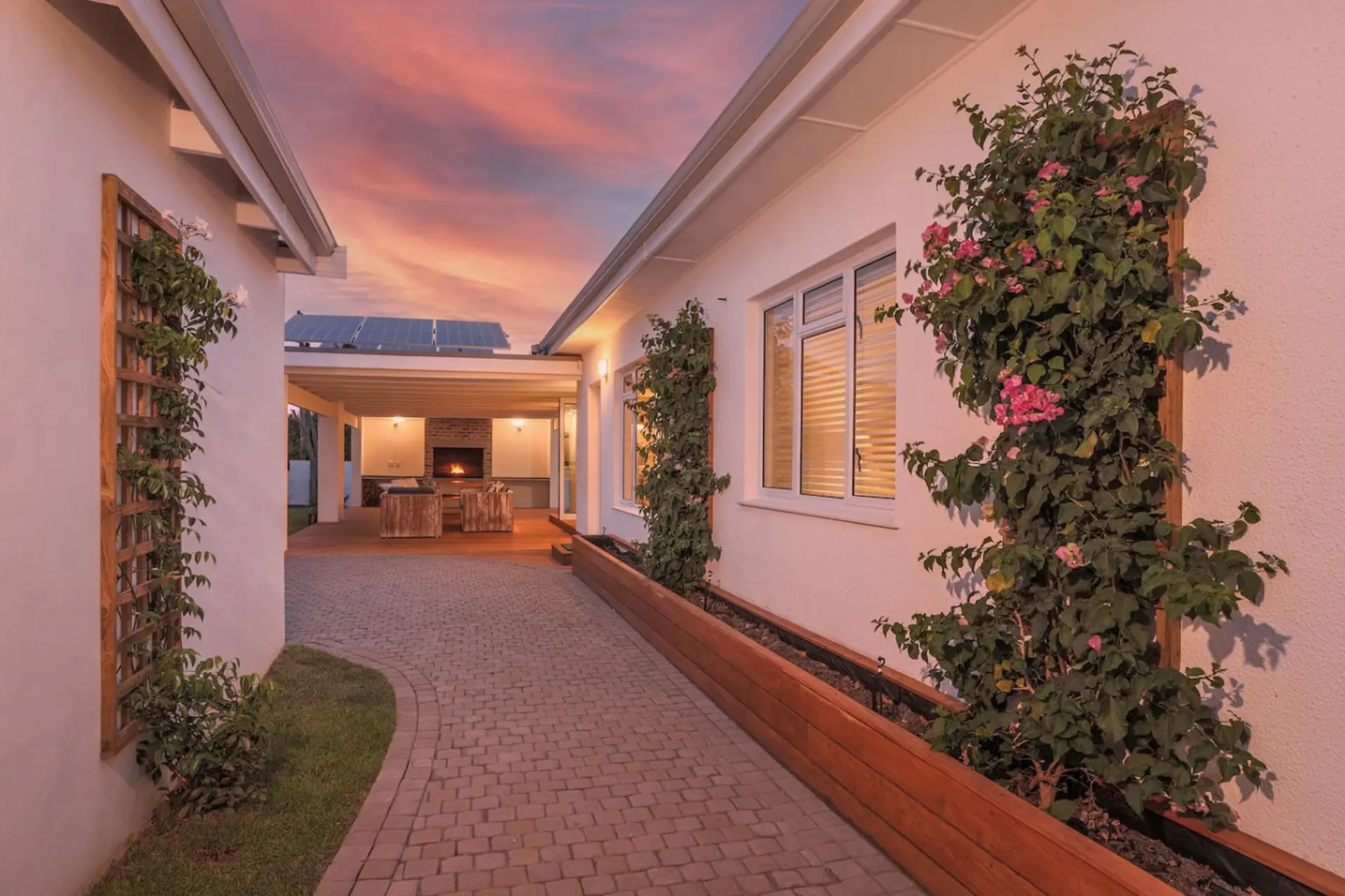 Outdoor living space with a fireplace and seating area, framed by bougainvillea.