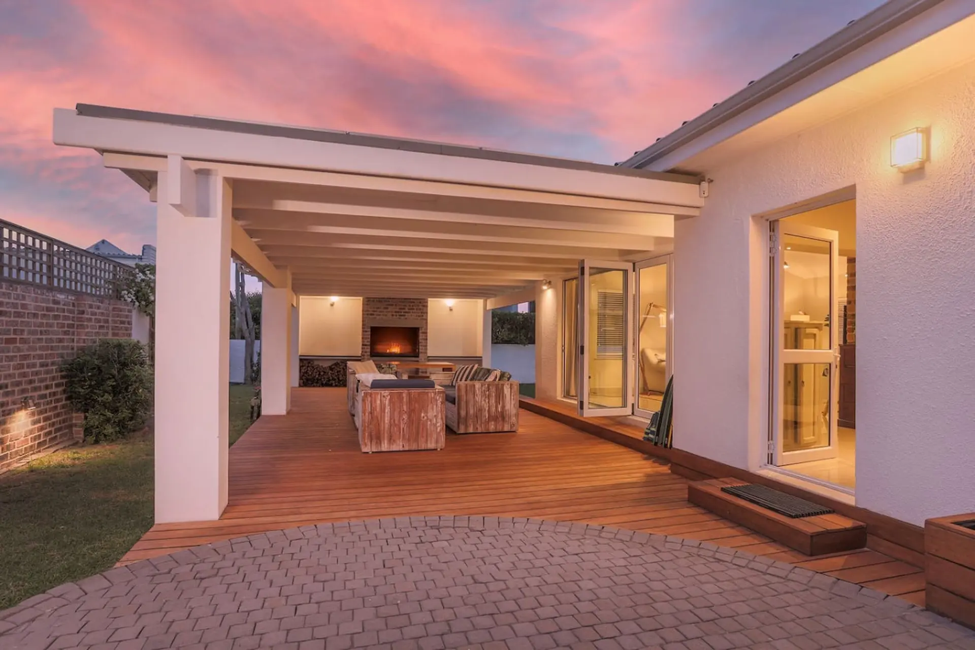 An outdoor patio with a fireplace, seating, and a sunset sky.