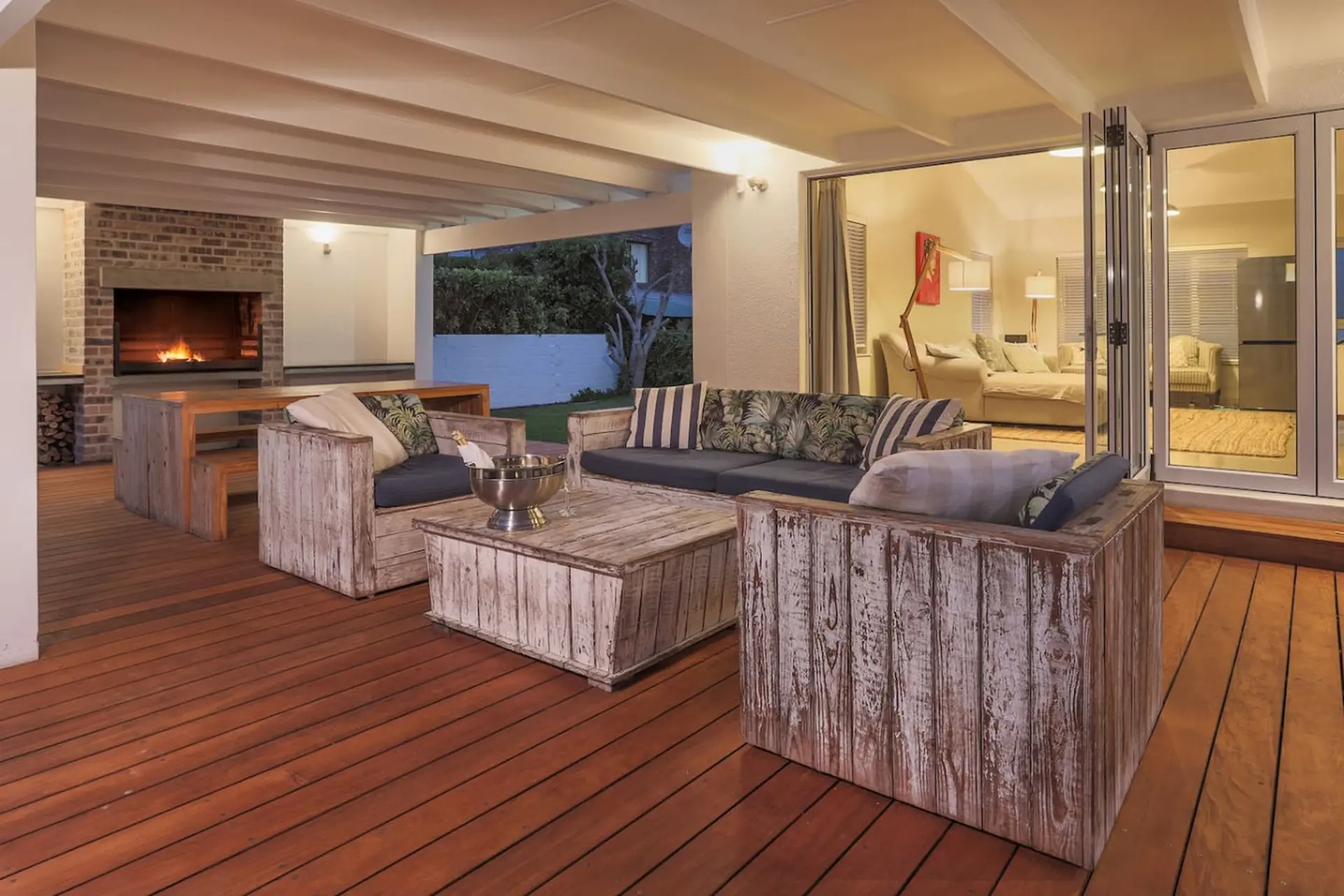 Outdoor patio with a fireplace, seating, and a champagne bucket on a coffee table.