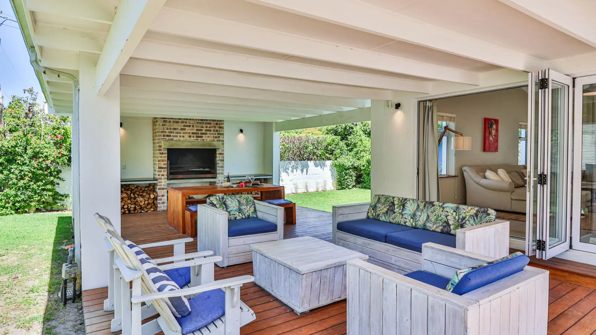 Covered patio with outdoor seating, grill, and dining table overlooking a grassy yard.