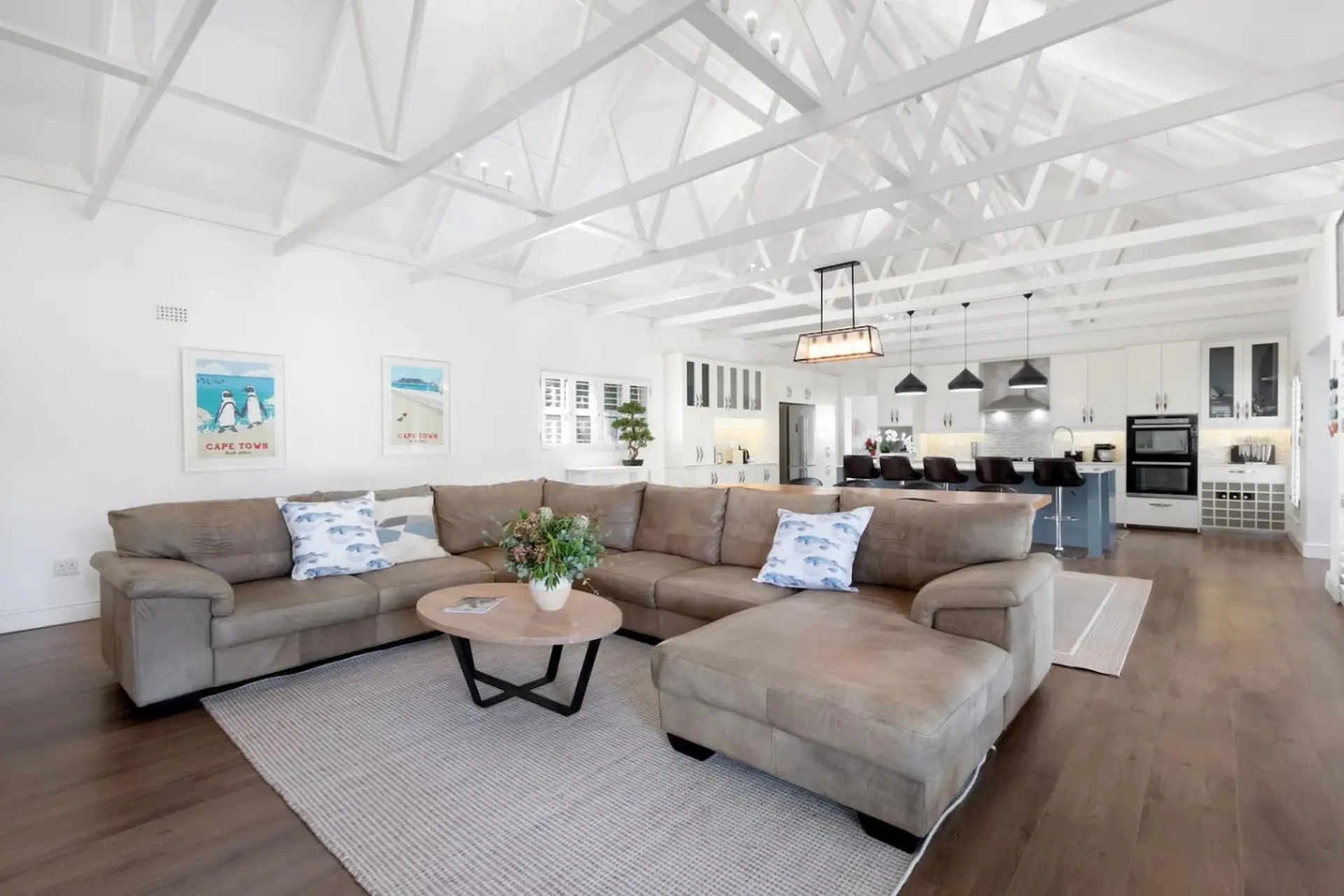 A spacious living room with a large sectional sofa, coffee table, and kitchen in the background.