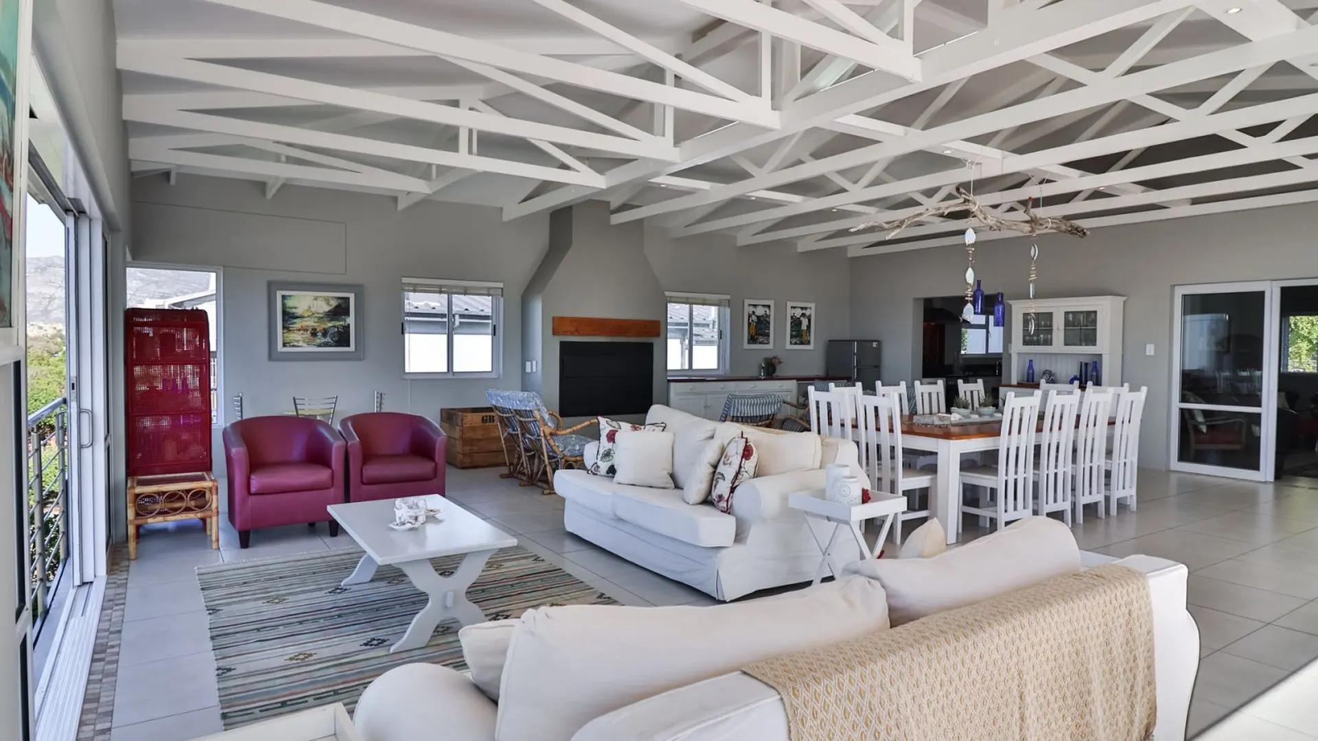 A spacious living room with a white sectional sofa, dining table, and fireplace.