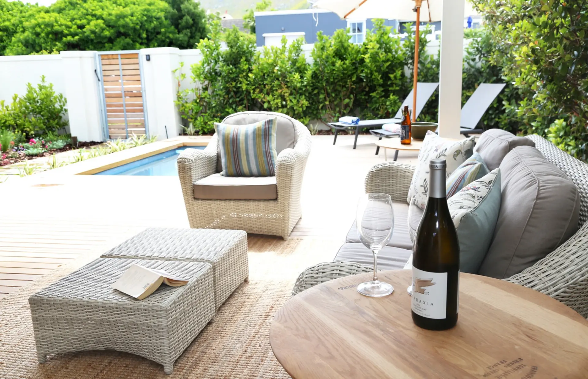 A relaxing outdoor seating area by a pool with a wicker sofa, chair, and ottomans.