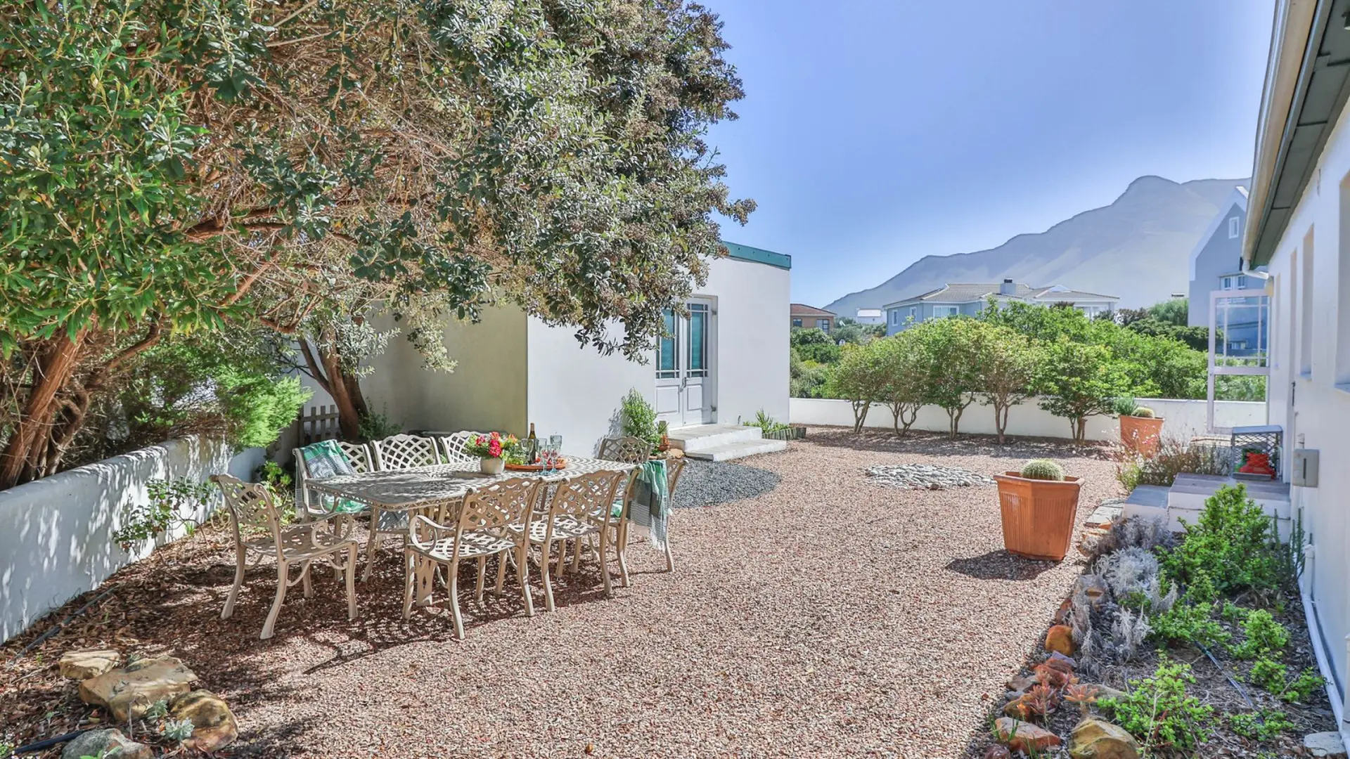 An outdoor dining set sits under a tree with a scenic mountain view in the background.