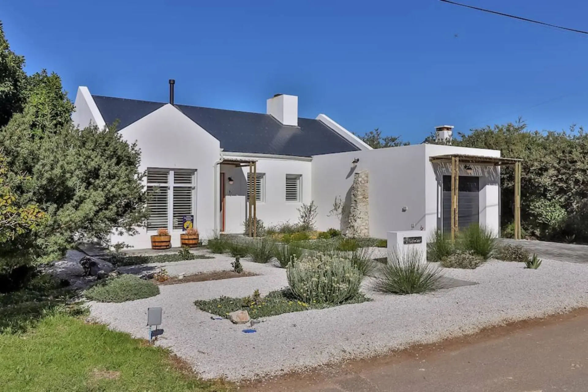 A modern white house with a dark roof and minimalist landscaping.
