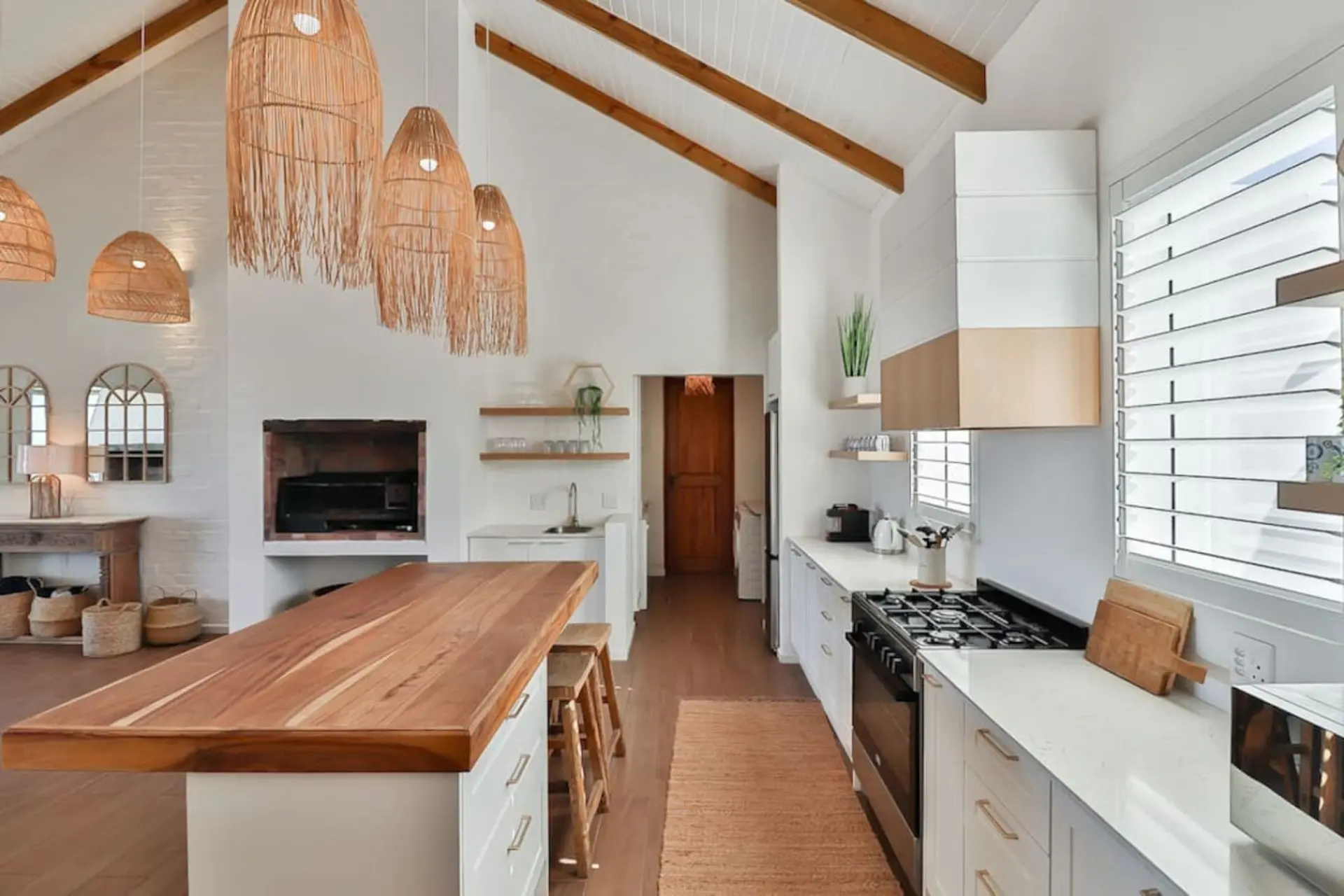 A bright kitchen with white cabinets, a wooden island, and pendant lights.
