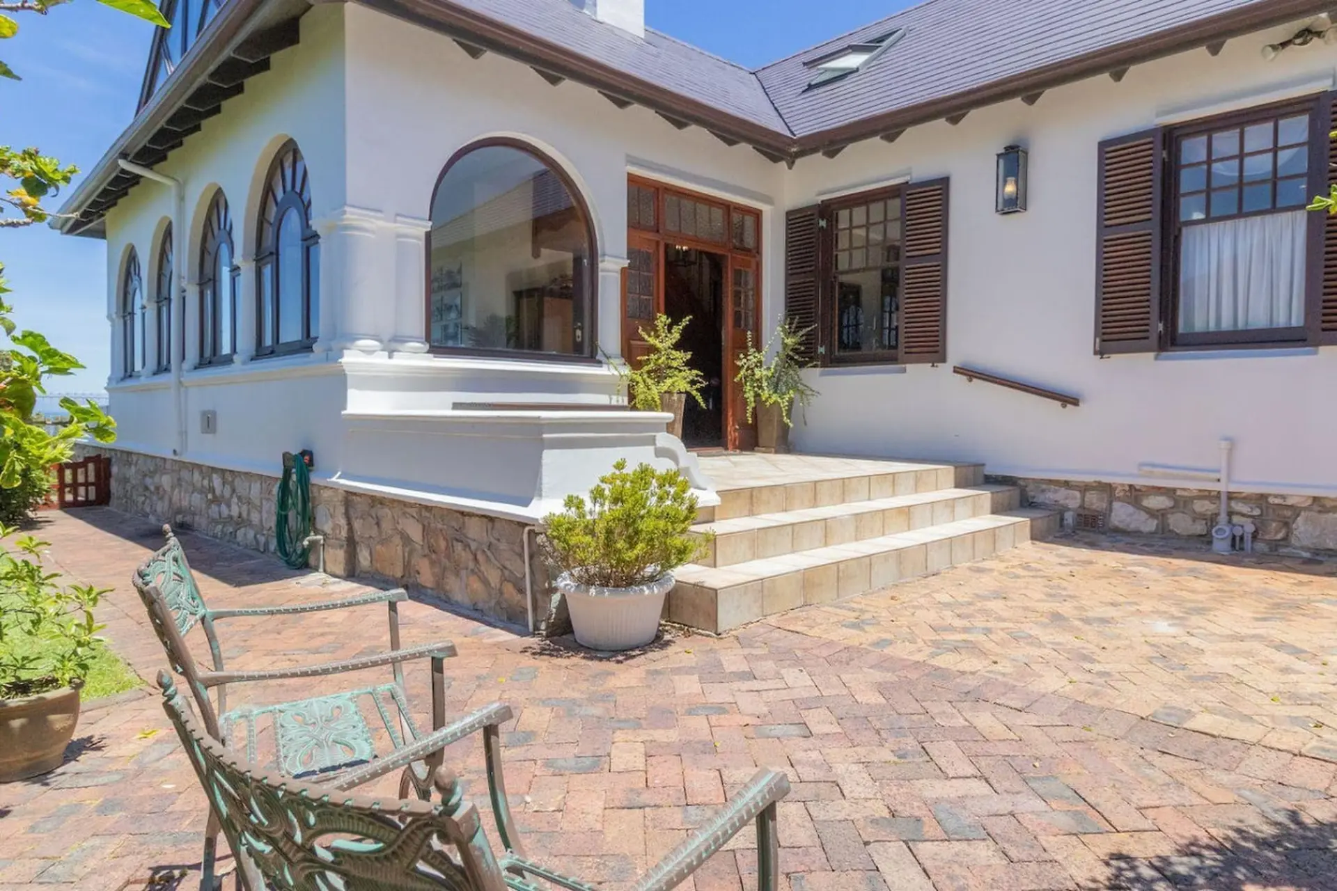 A white house with arched windows and a brick patio.