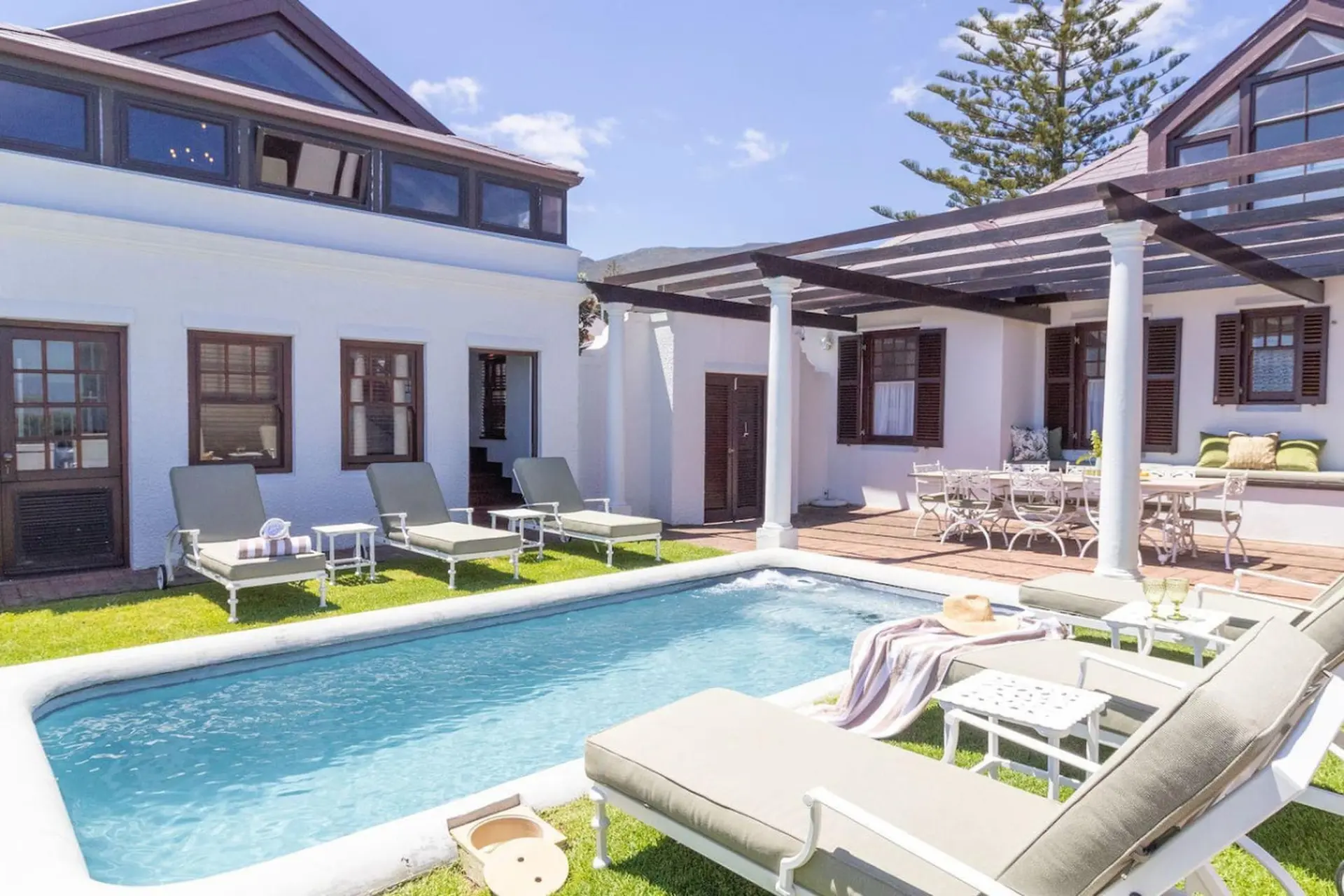 A sunny courtyard with a pool, lounge chairs, and an outdoor dining area.