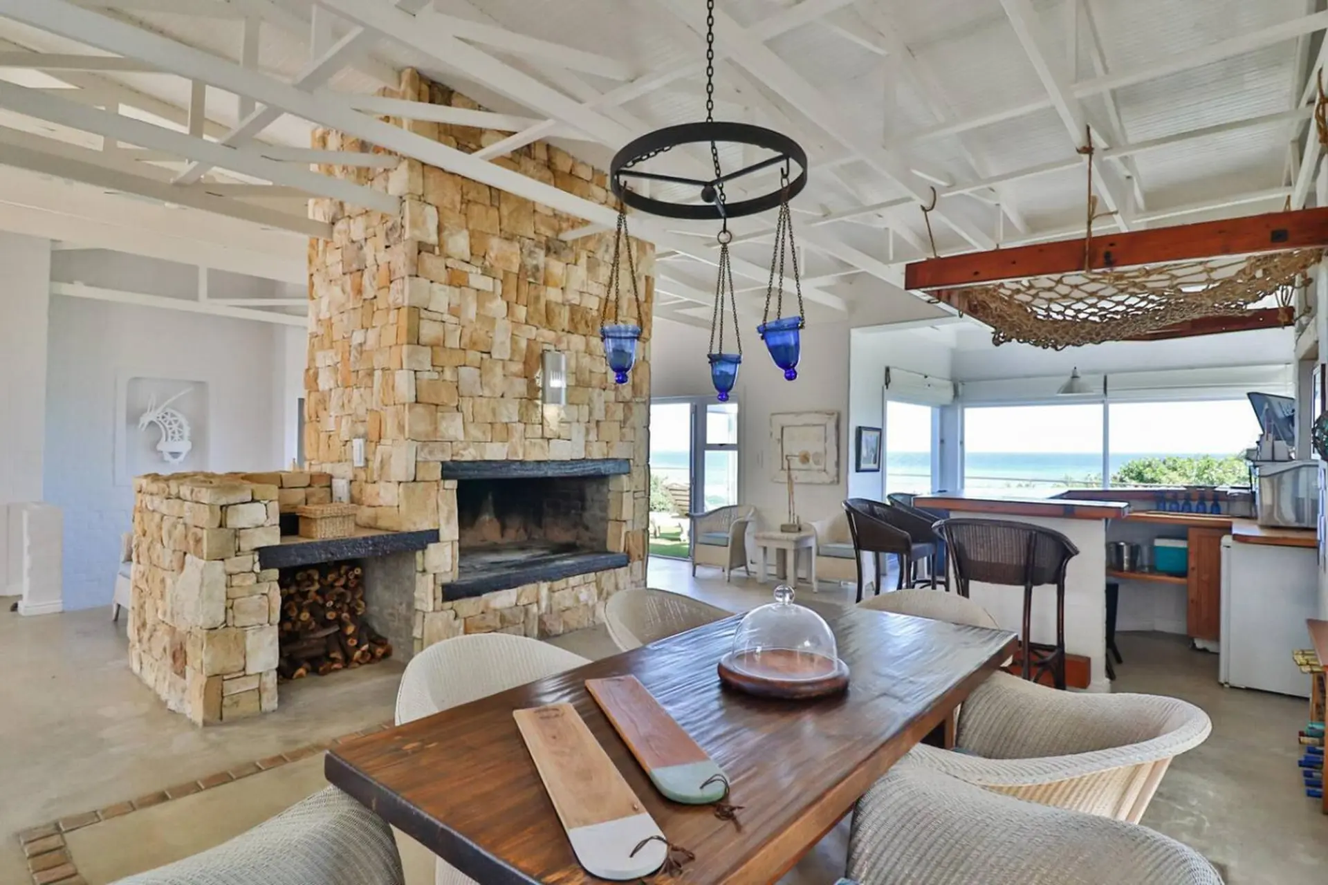 Living room with stone fireplace, dining table, and ocean view.