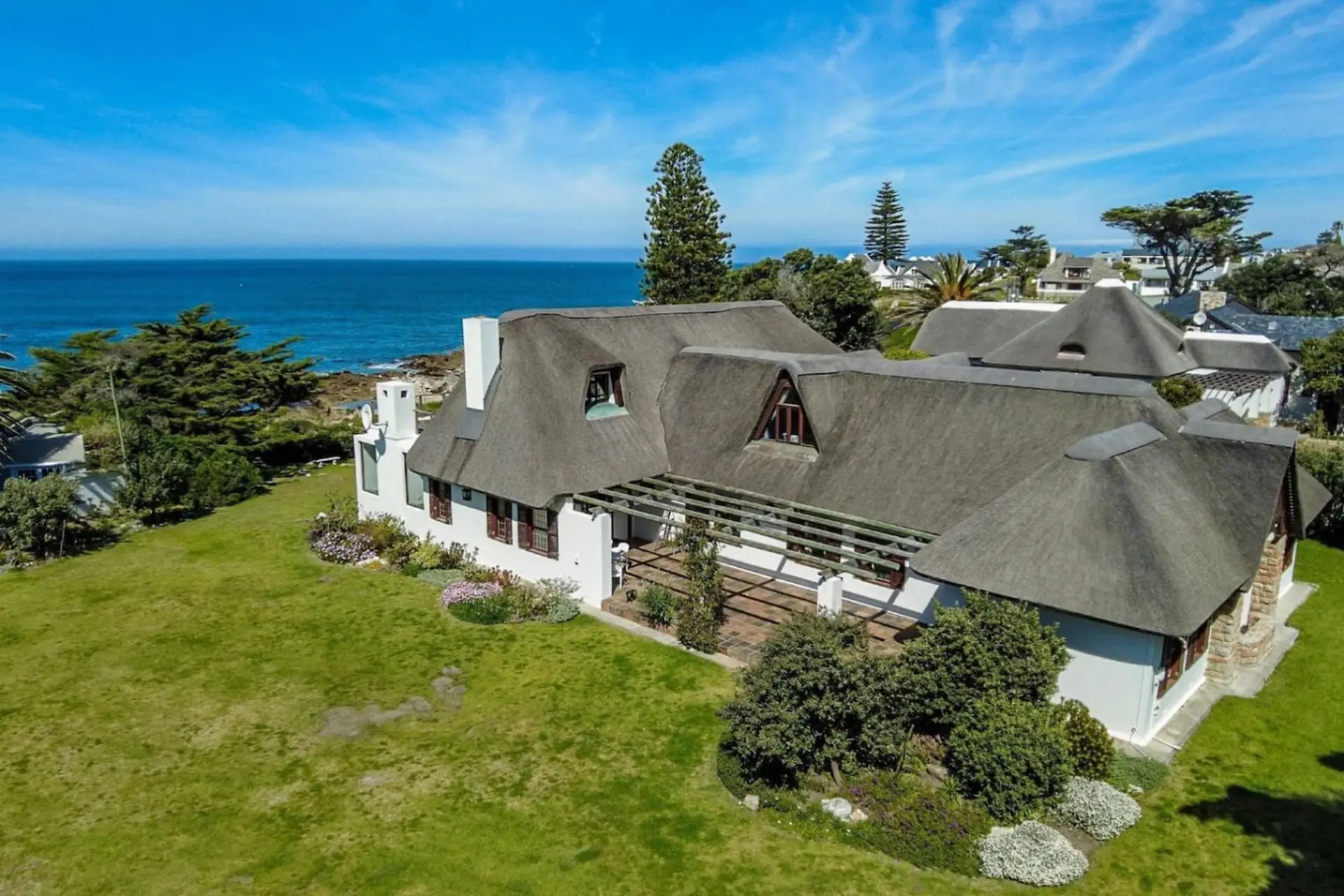 A white house with thatched roofs near the ocean.