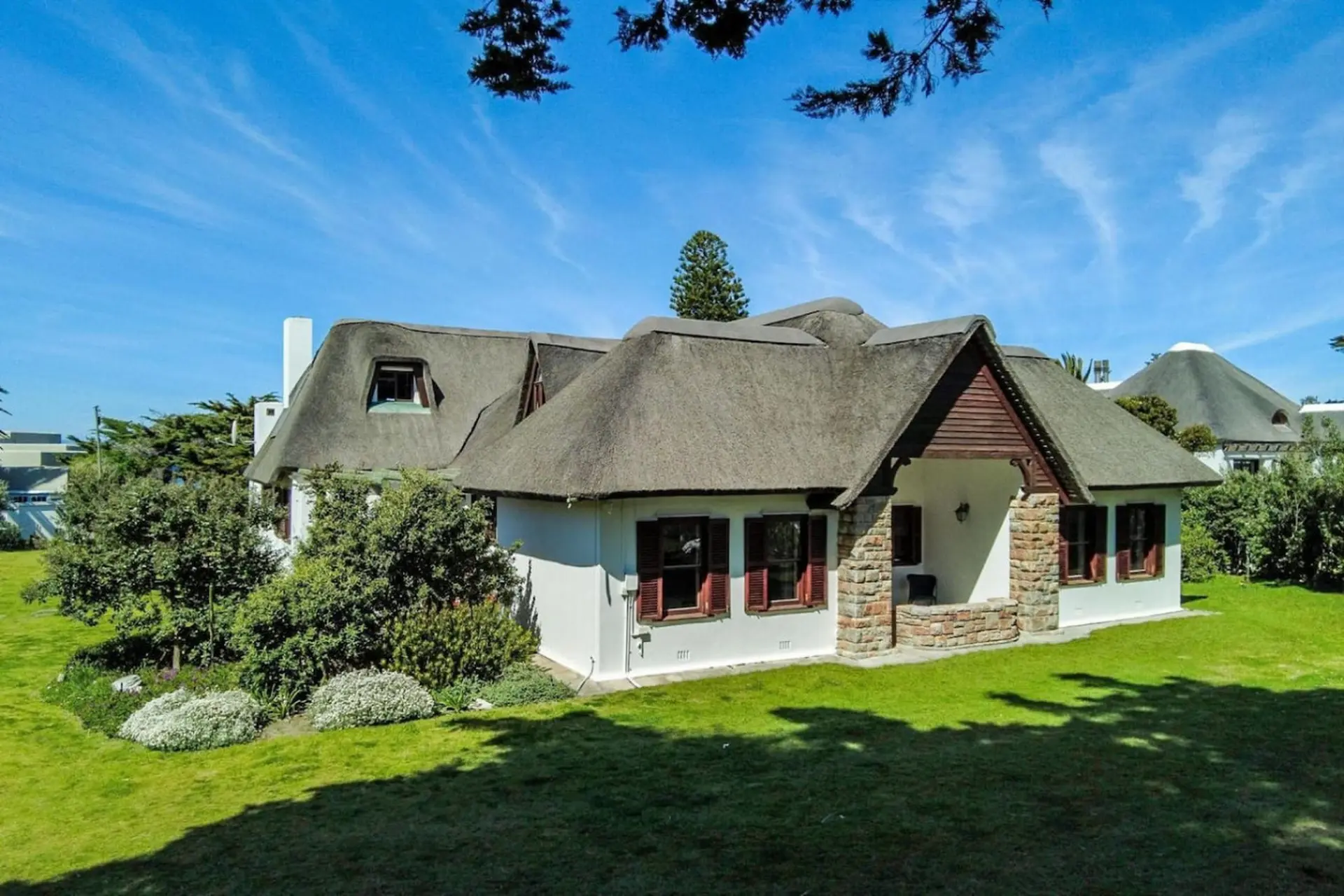 A white house with a thatched roof on a sunny day.