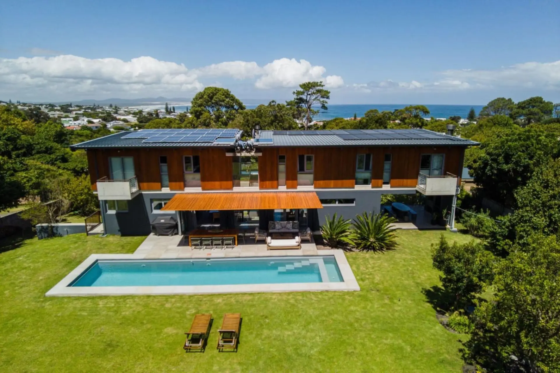 Modern house with pool, solar panels, and ocean views.