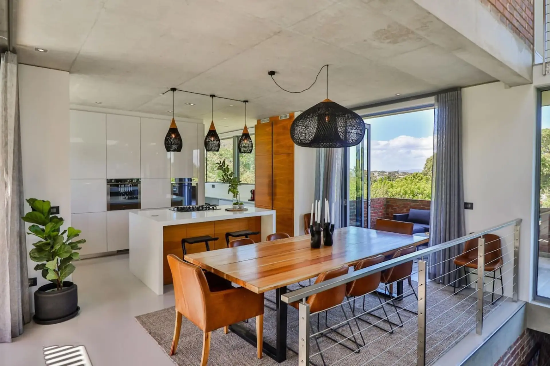 A modern kitchen and dining area with a large wooden table and leather chairs.
