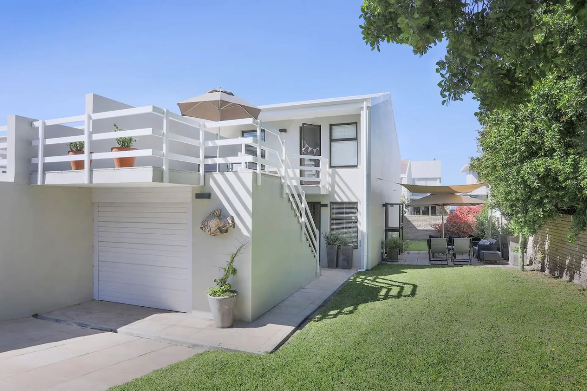 A white house with an outdoor seating area and a grassy yard.