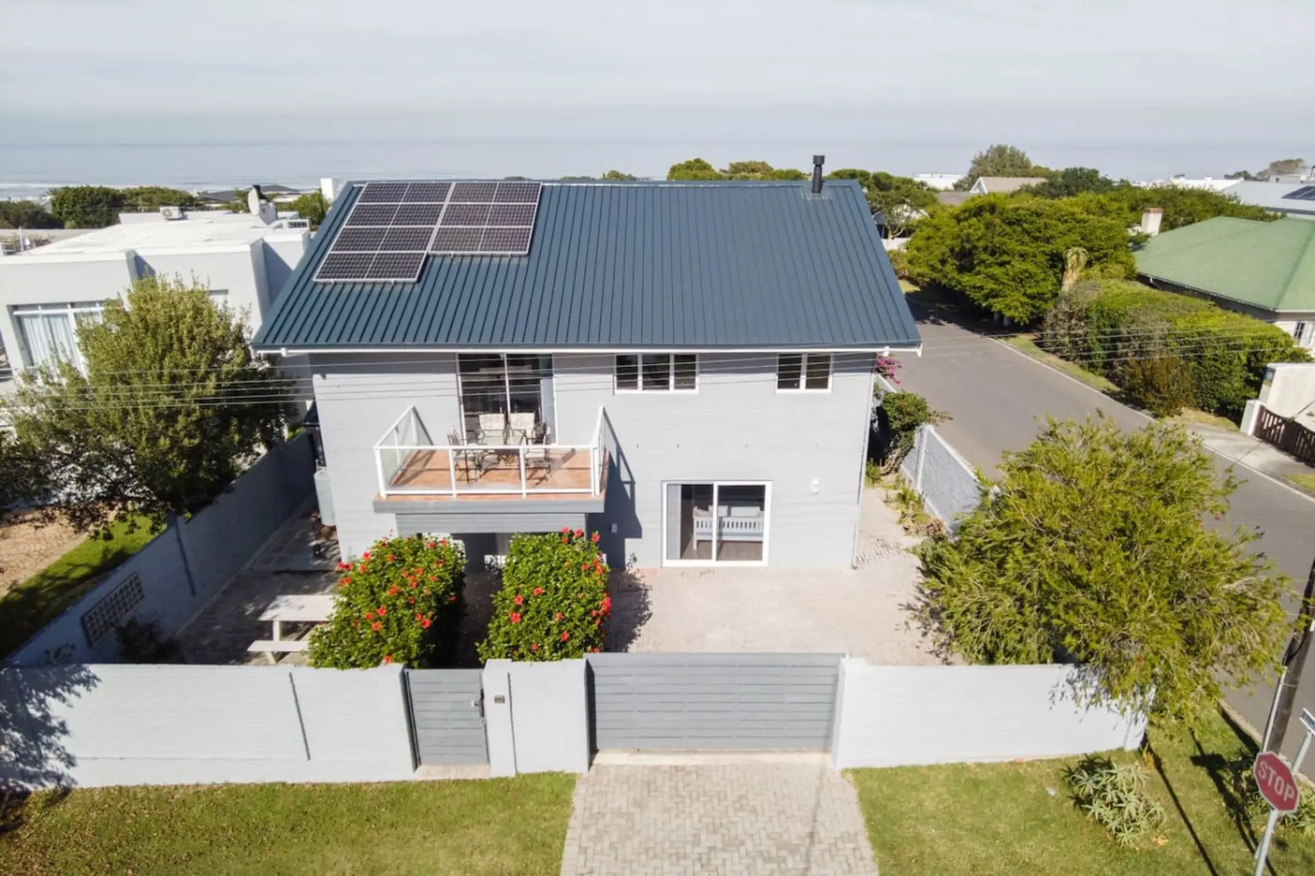 Aerial view of a modern gray house with a gray metal roof and solar panels.