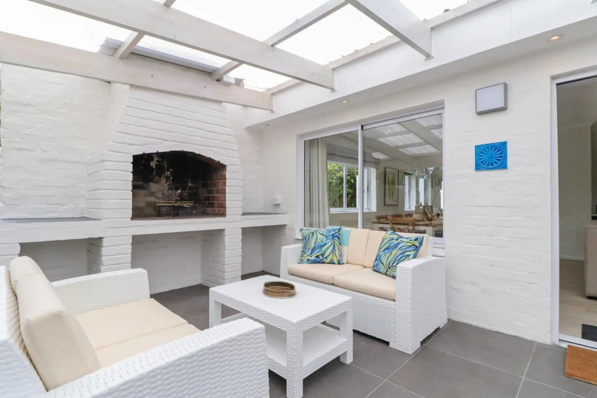 White brick fireplace and seating area with white furniture and tropical cushions.