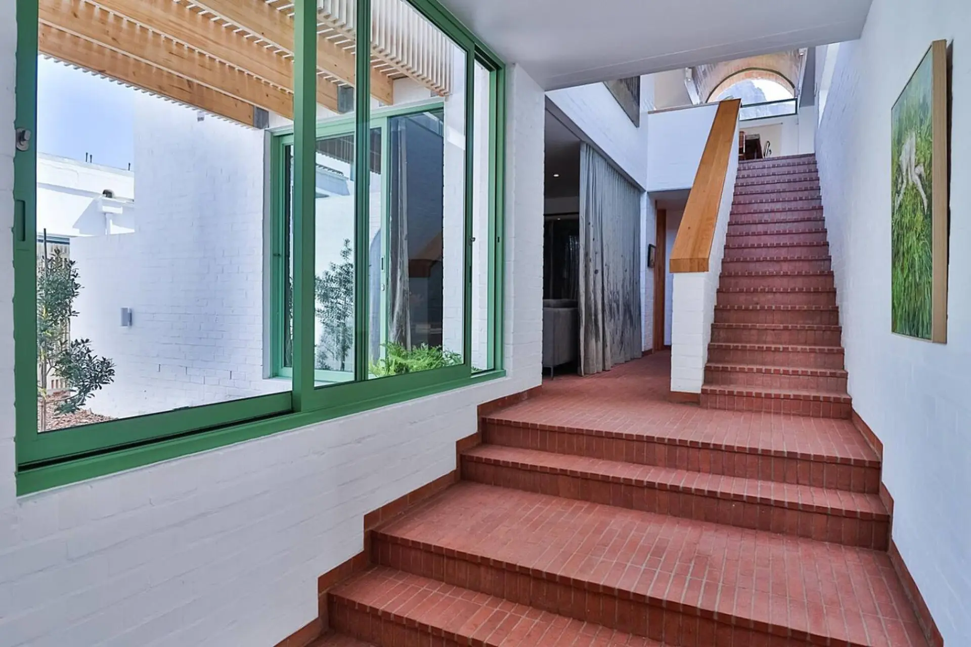 A hallway with a brick staircase and large windows.