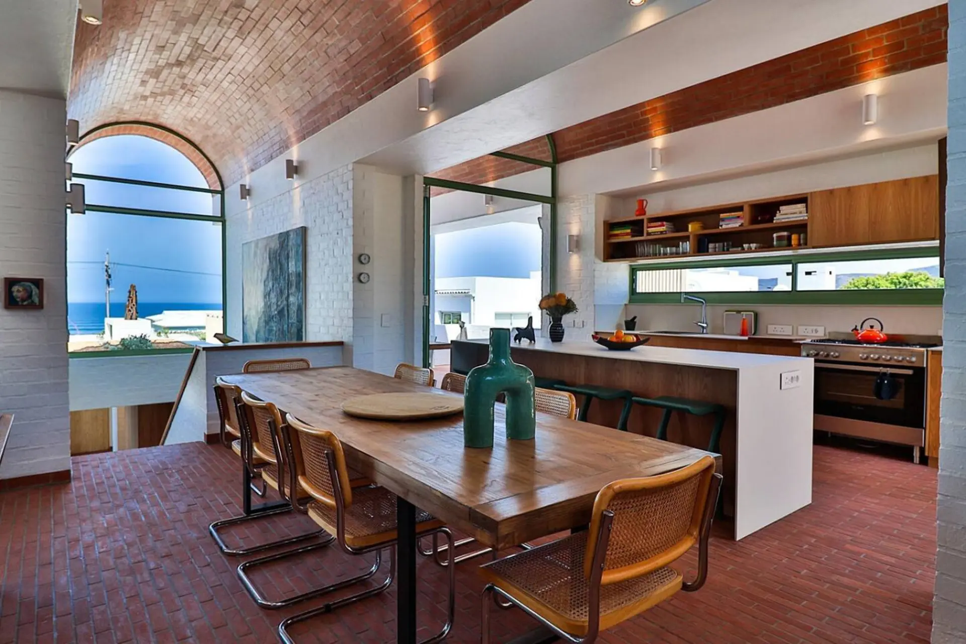Modern dining room and kitchen with arched ceiling and ocean view.