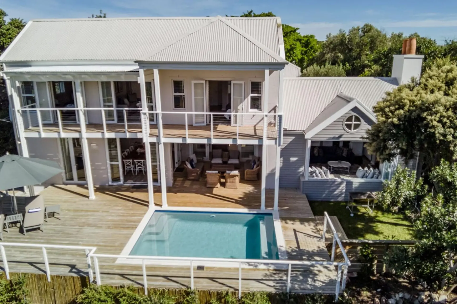 Aerial view of a modern villa with a pool, deck, and surrounding greenery.