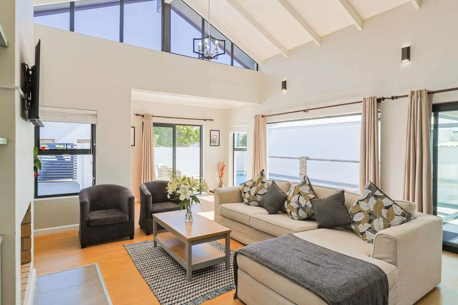 A modern living room with a sectional sofa, armchairs, coffee table, and large windows.