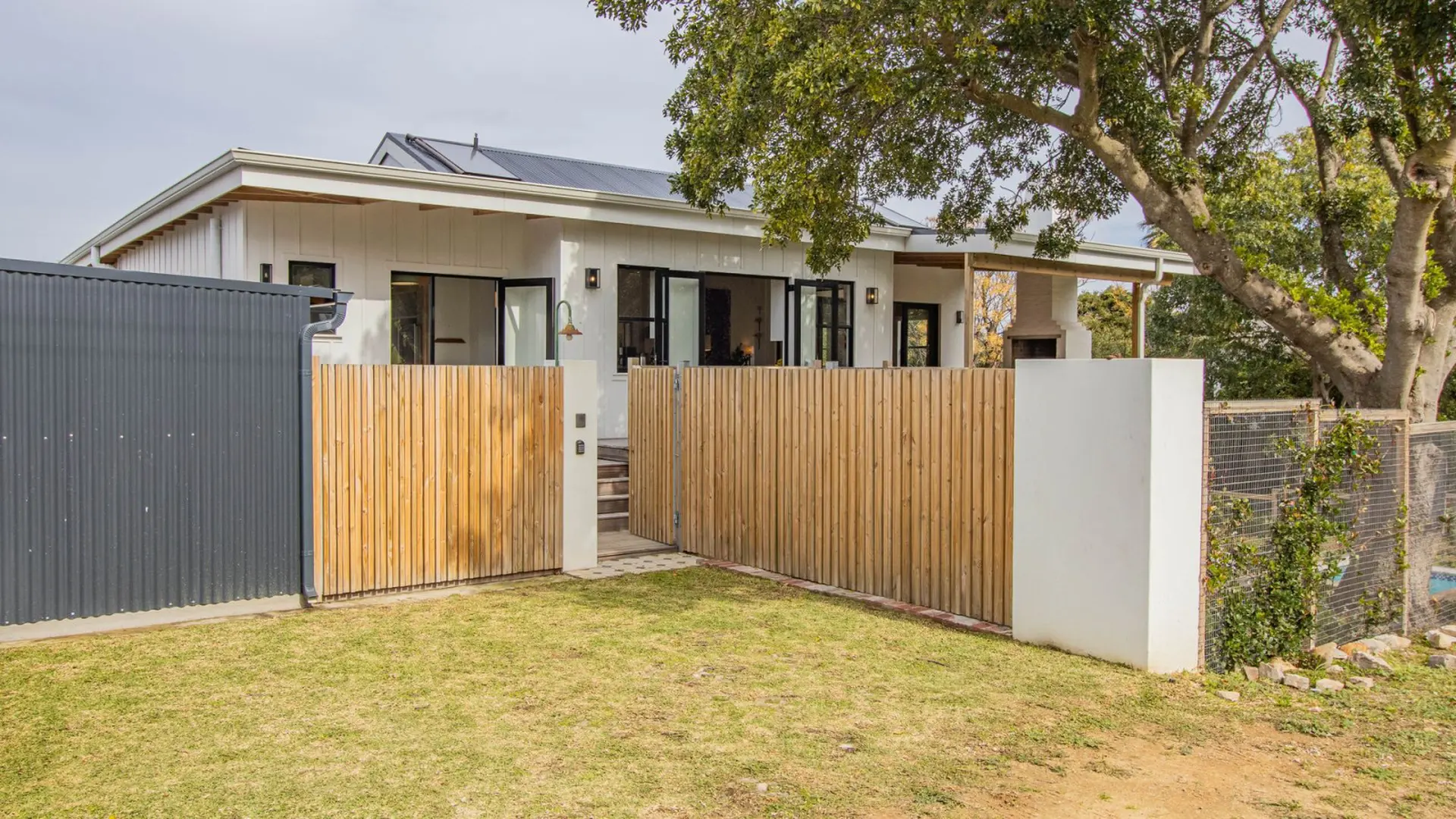 Modern white house with a wooden fence and gate in front of it.